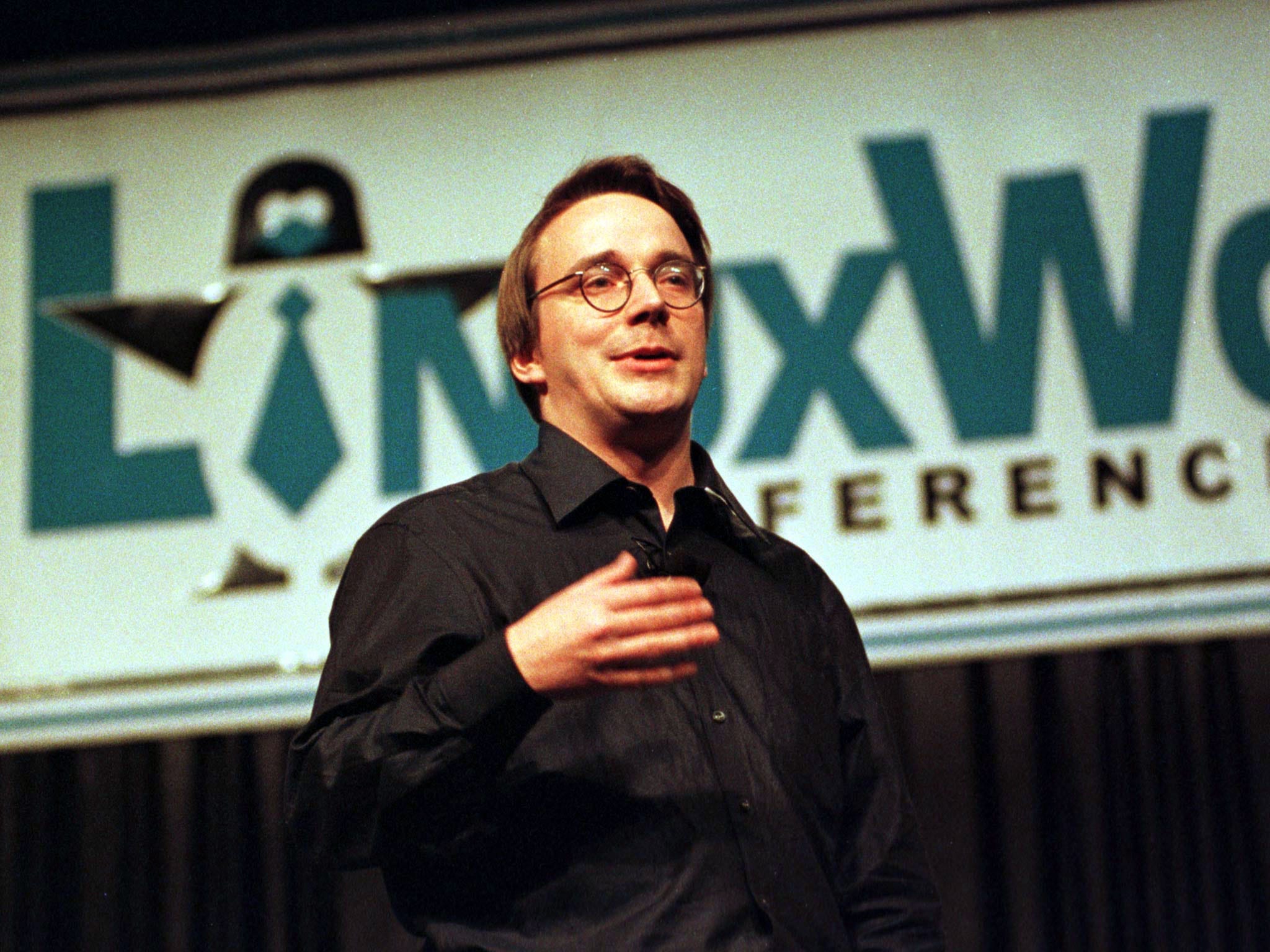 A young Linus Torvalds speaking on stage at the Linux World conference in 1999