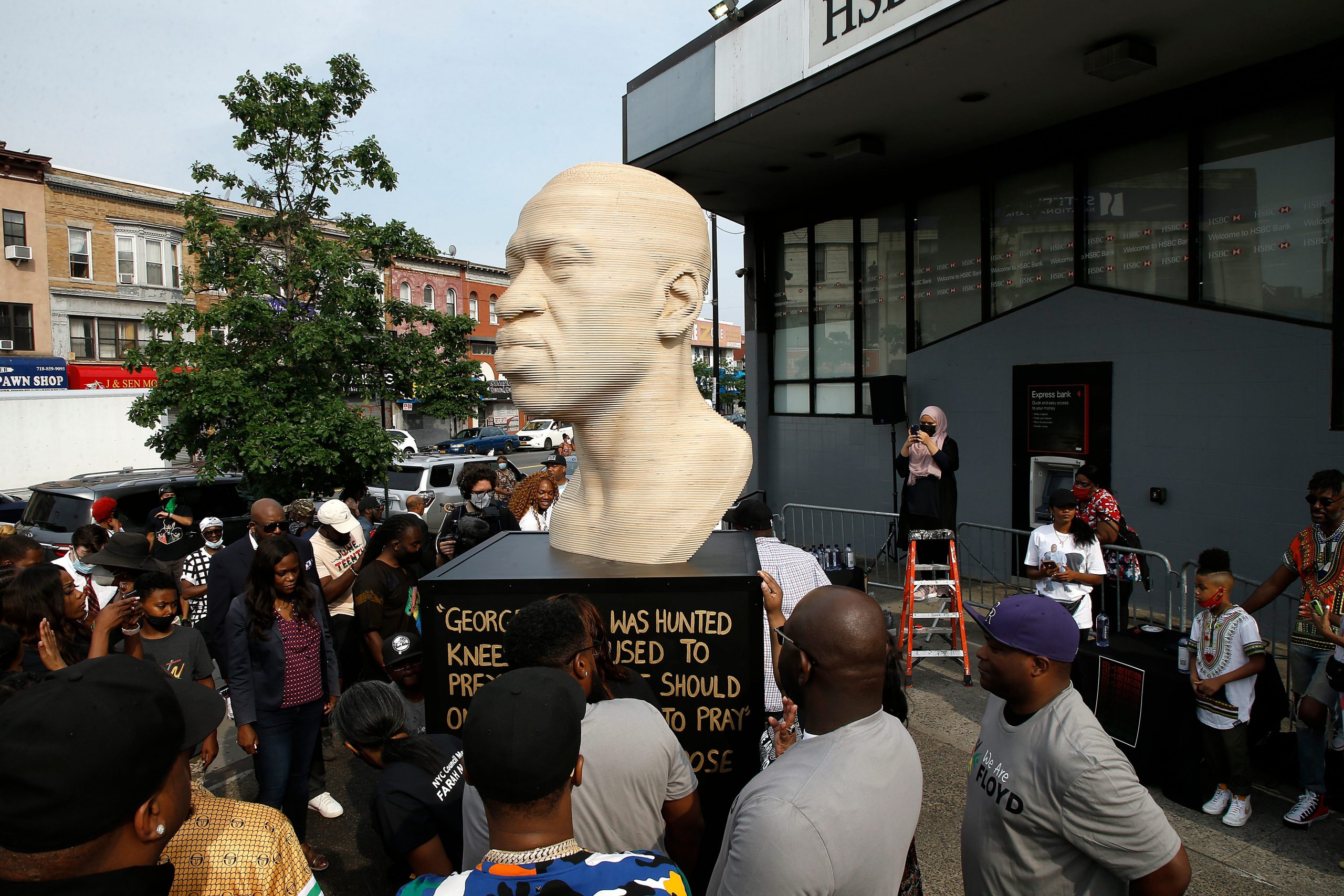 A crowd gathers next to a George Floyd statue in Brooklyn, New York.