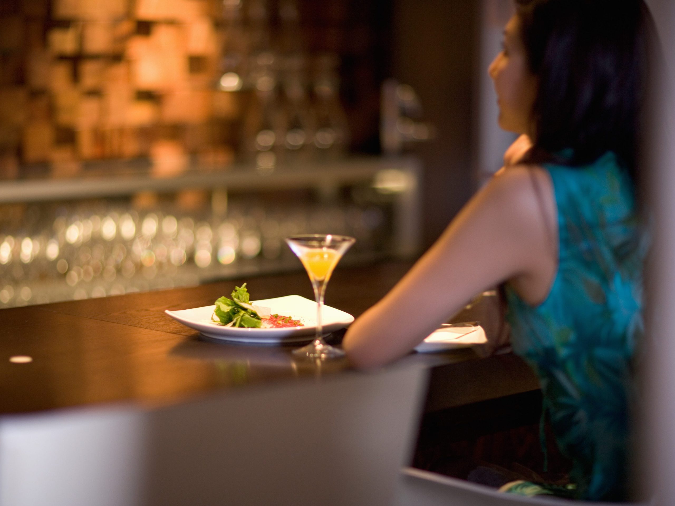 A stock photo of a woman sitting alone at a bar