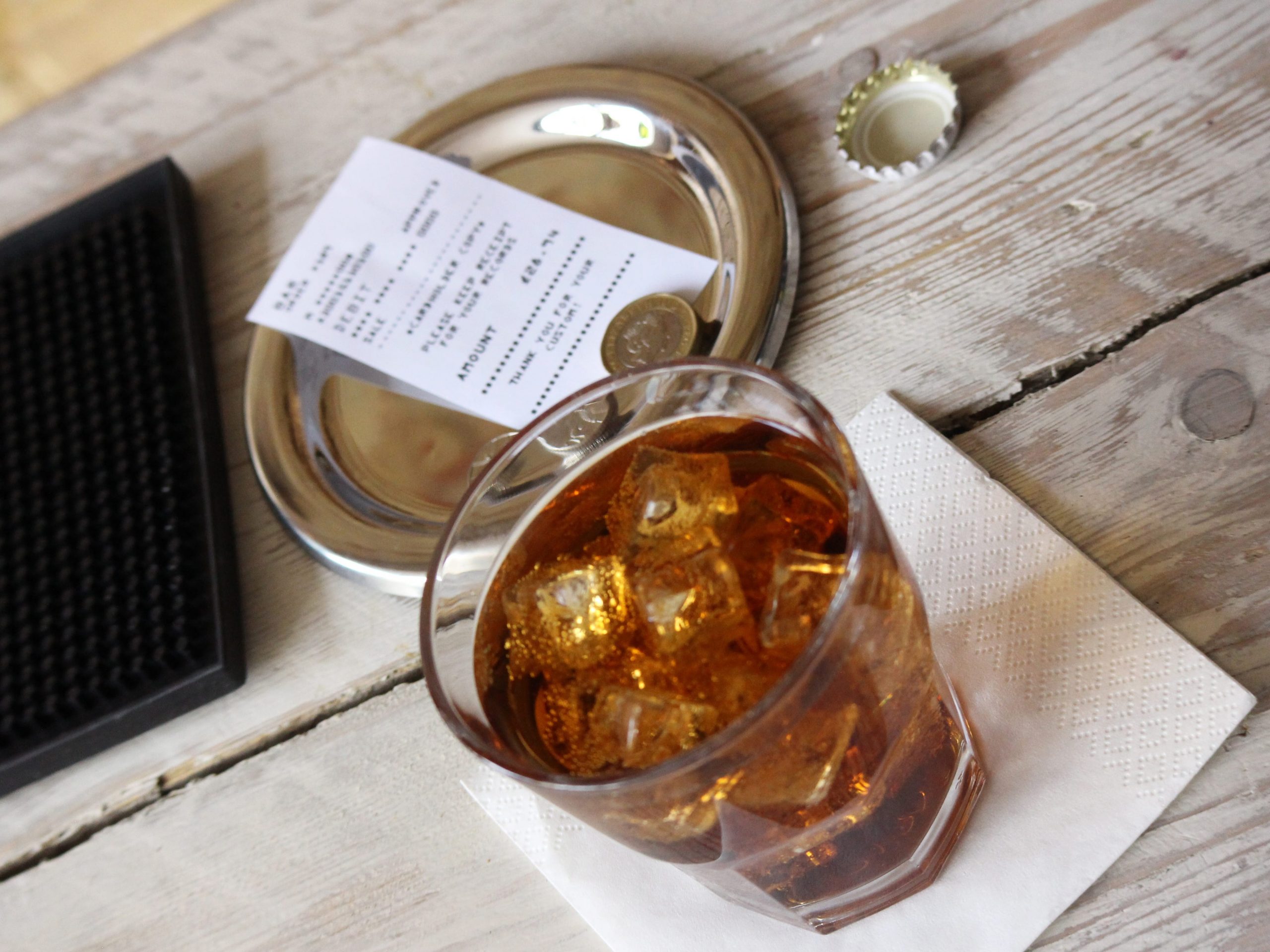 A drink on a bar counter with tip tray in shot