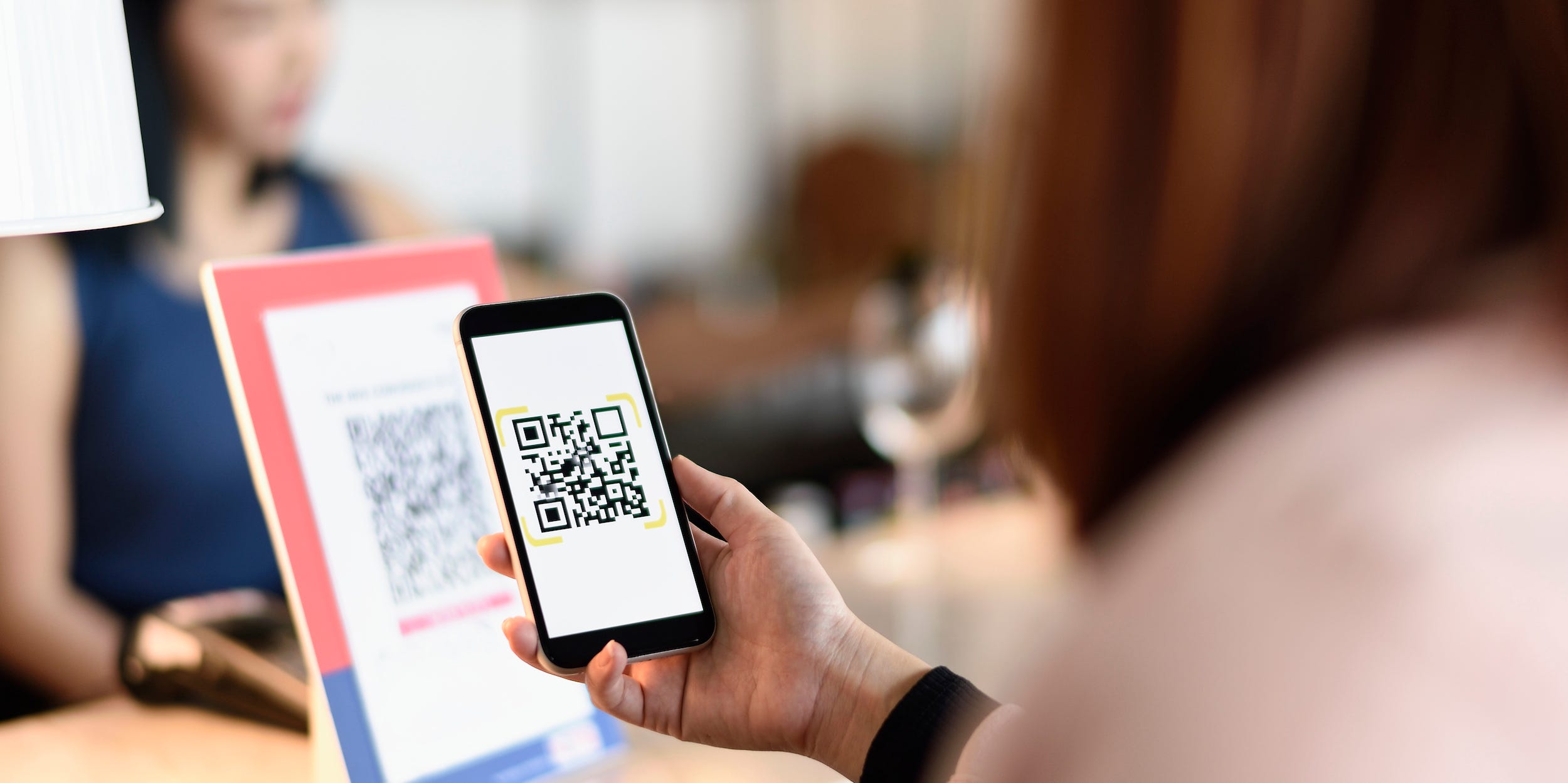 woman scanning QR code with smartphone at store