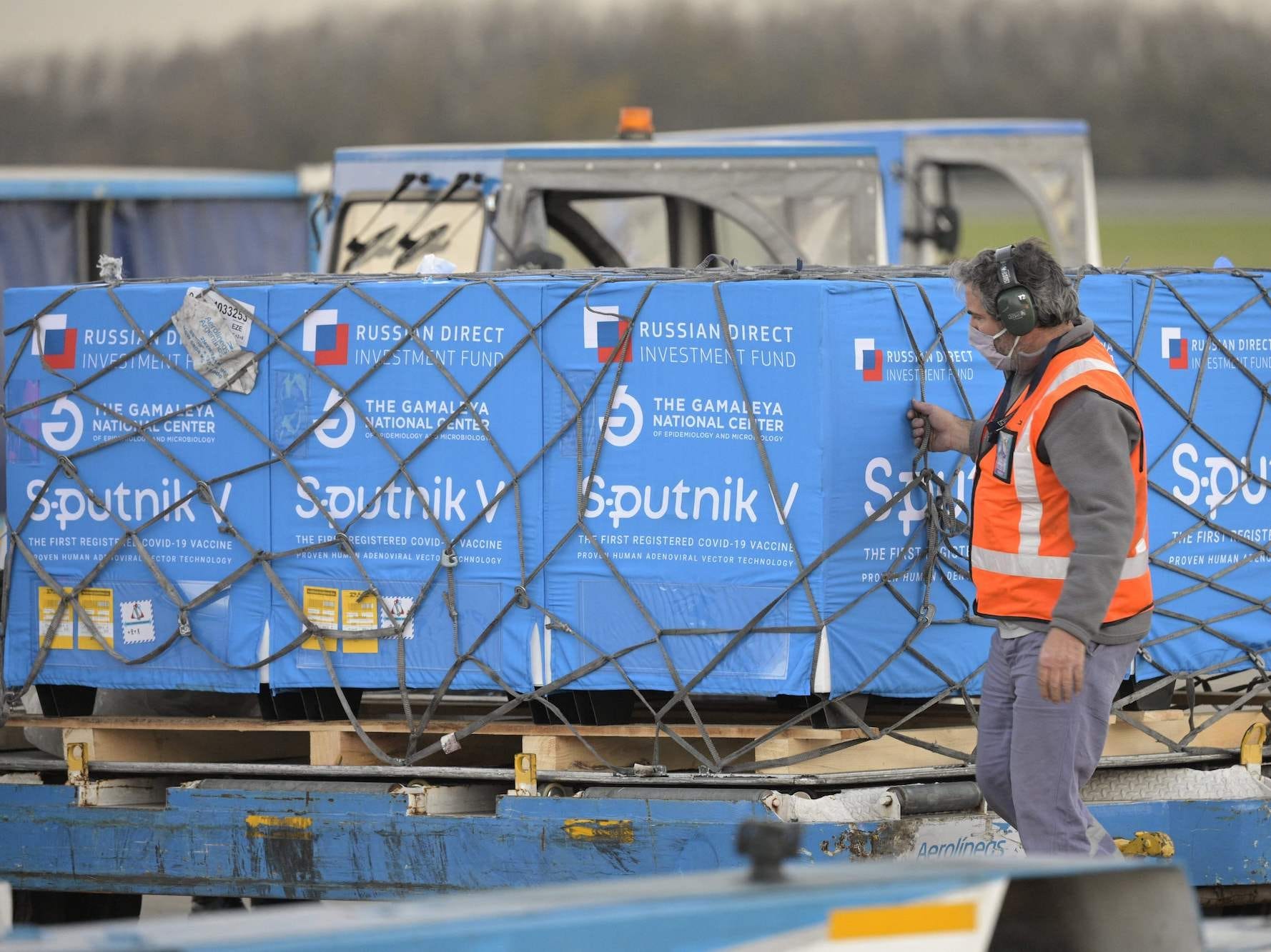 A man wearing a high-vis jacket inspects crates stamped with the logo of Russia's Sputnik V vaccine, on June 8, in Buenos Aires, Argentina