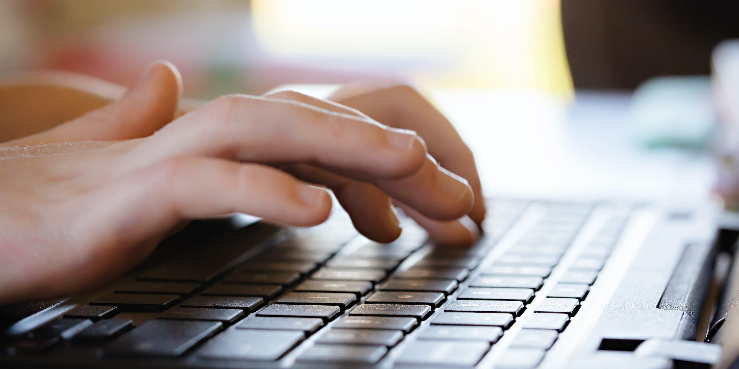 hands typing on laptop keyboard PC