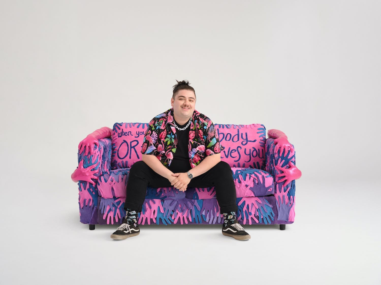 Brian Lanigan sits on his purple and pink couch.