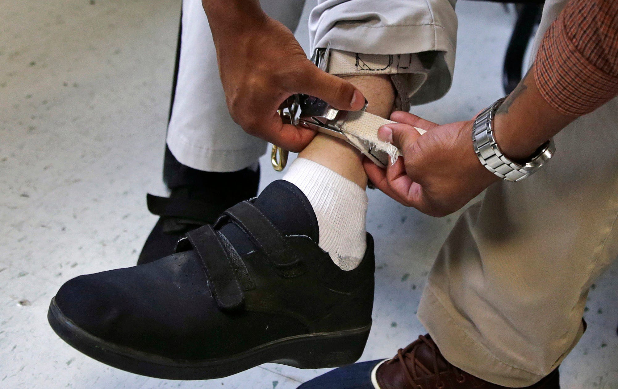 FILE - In this Aug. 13, 2014 file photo, a therapist checks the ankle strap of an electrical shocking device on a student during an exercise program at the Judge Rotenberg Educational Center in Canton, Mass. The student, who was born with a developmental disorder, wears the device so administrators can control violent episodes. On Wednesday, March 4, 2020, the U.S. Food and Drug Administration announced it is banning a class of controversial devices used to discourage aggressive, self-injurious behavior in patients with mental disabilities. (AP Photo/Charles Krupa)