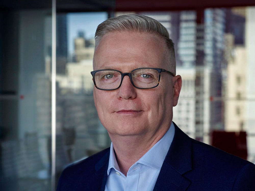 Howard Boville, head of IBM Hybrid Cloud Platform, poses in front of a building window