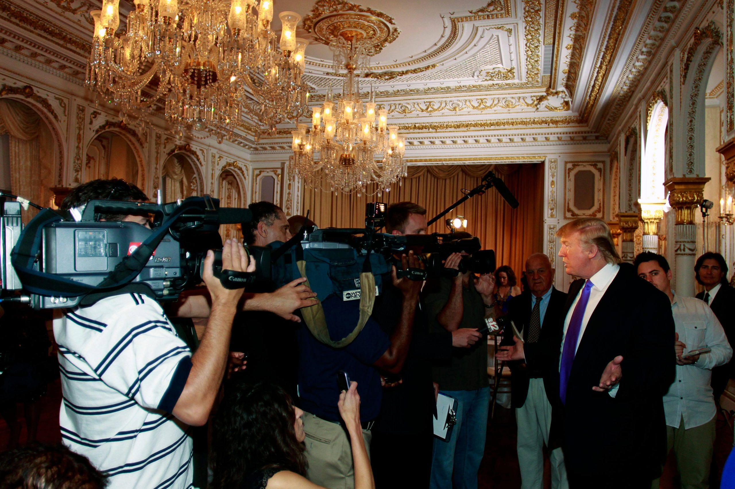 Trump flanked by cameras in Mar-a-Lago's gold-and-white ballroom in 2011