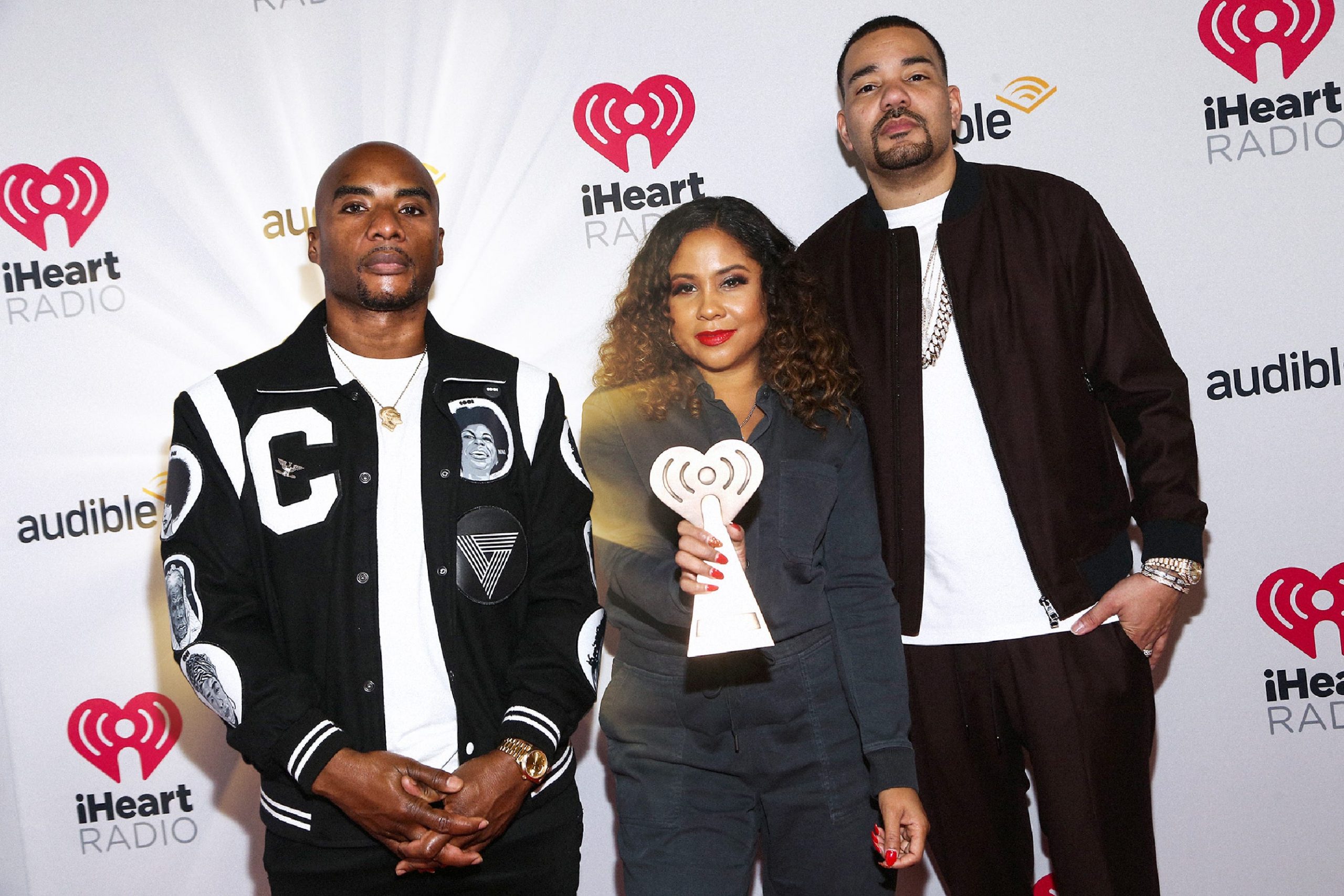 Charlamagne Tha God with a golden light radiating from behind him with Angela Yee and DJ Envy.