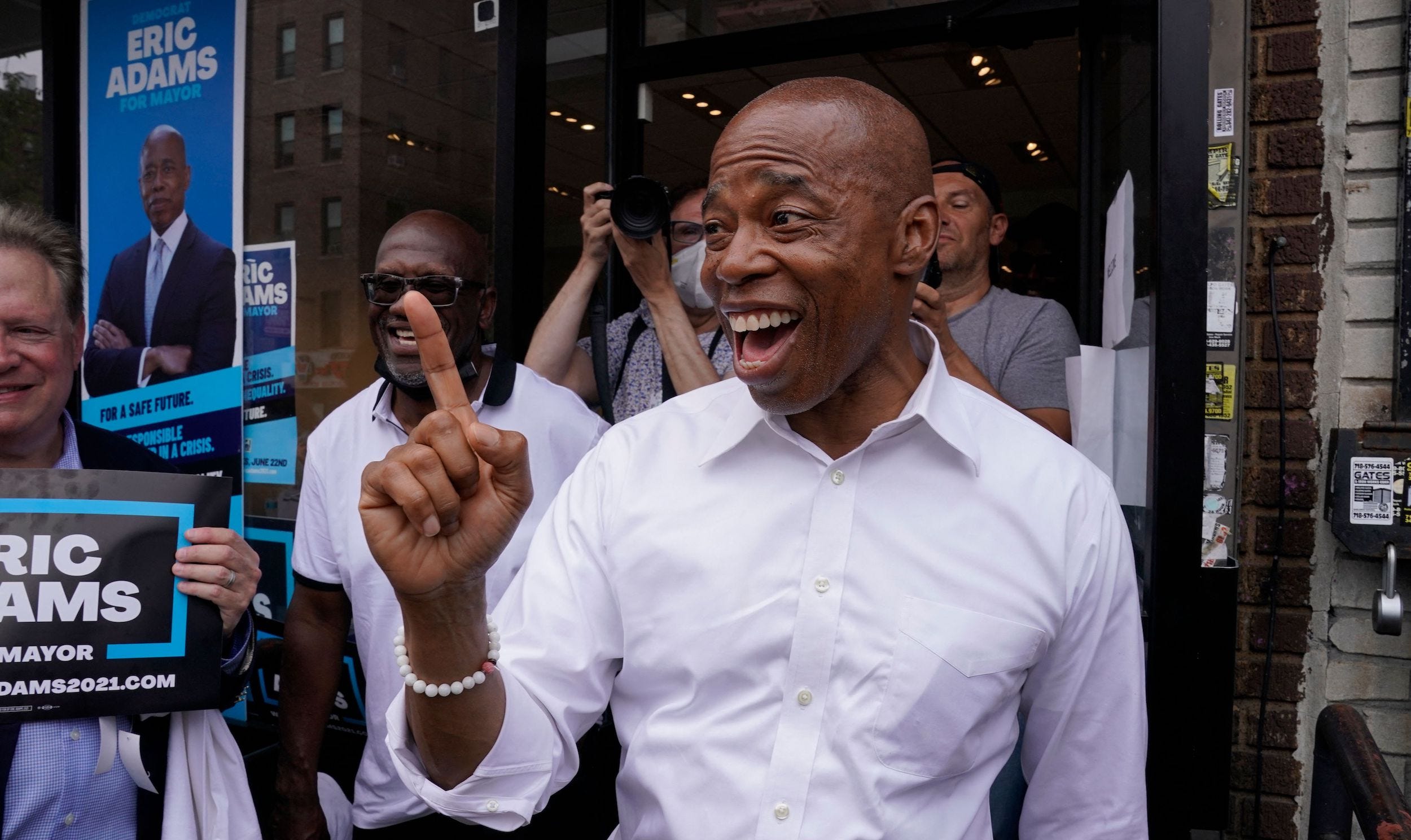 New York City mayoral candidate Eric Adams points his right finger in the air outside of his Brooklyn campaign office in Prospect Lefferts Gardens.