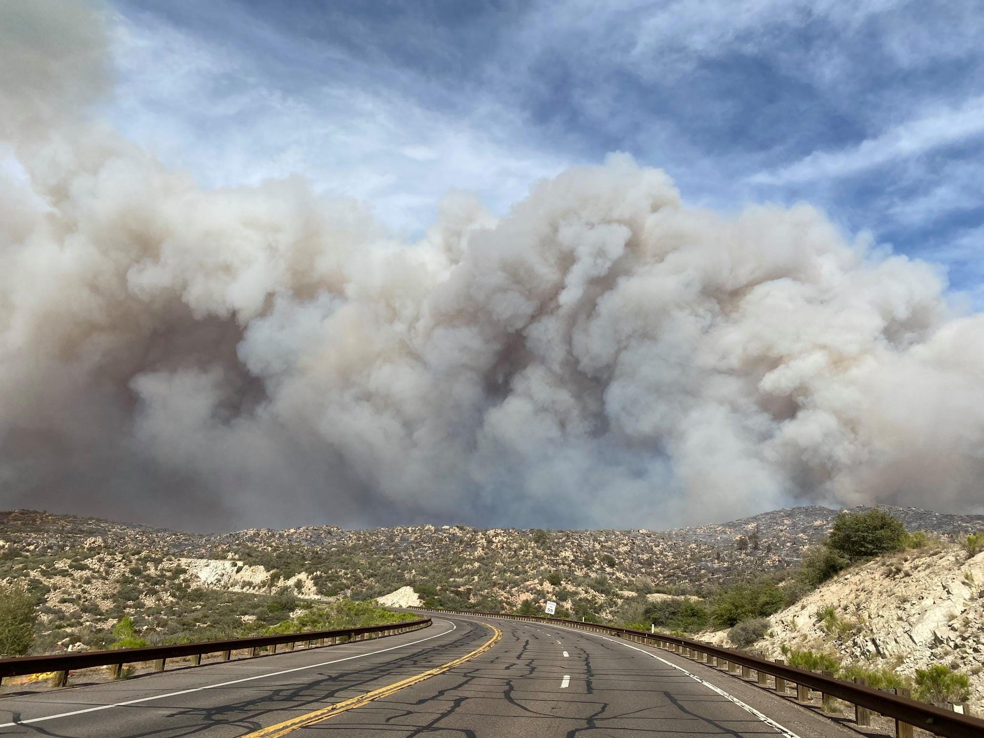 wildfire smoke plumes over dry hills and a highway road