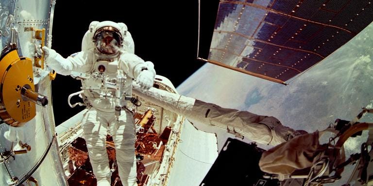 astronaut fixes hubble space telescope in spacesuit above earth