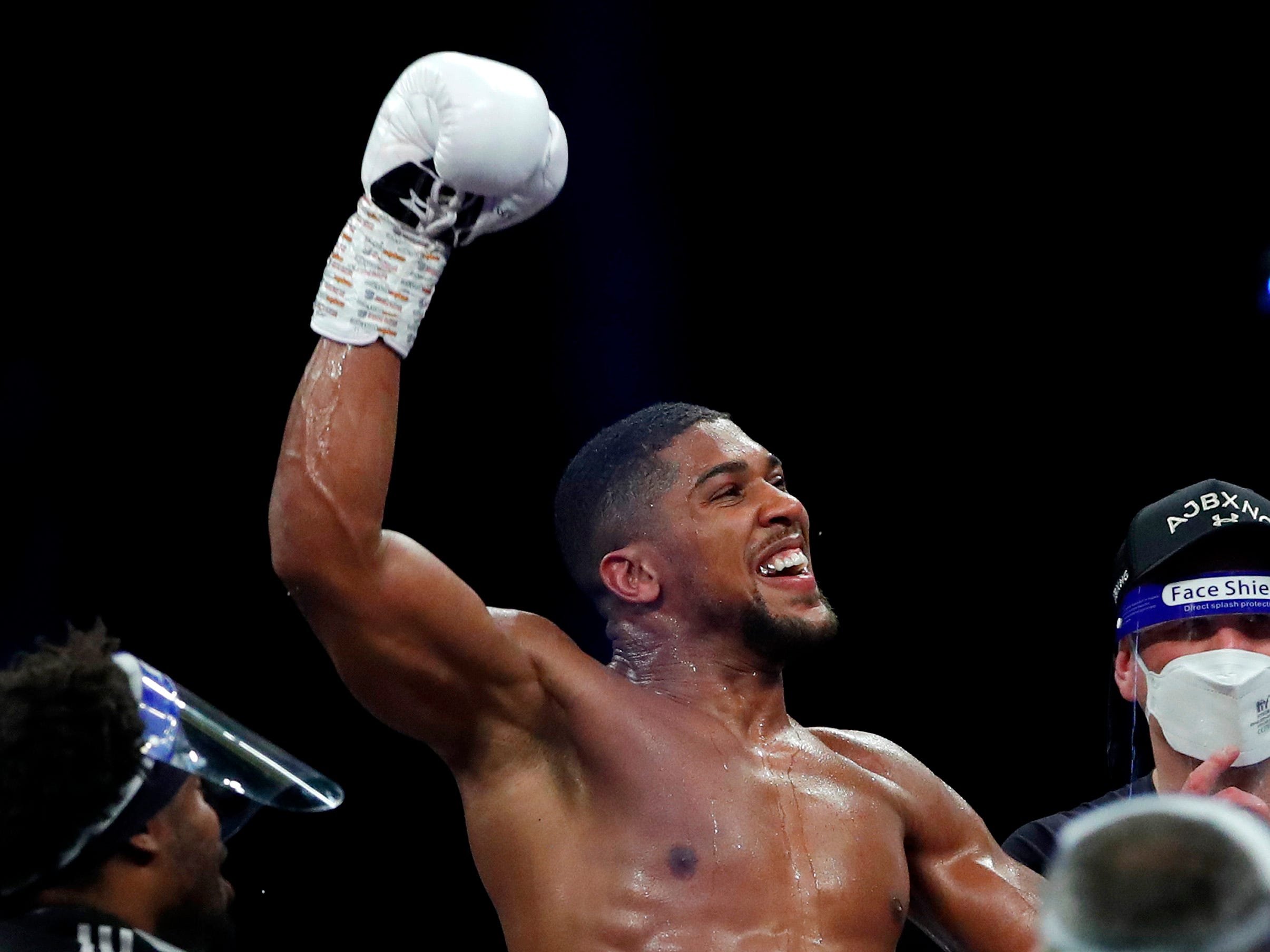 Anthony Joshua raises his right boxing glove in the air in celebration.