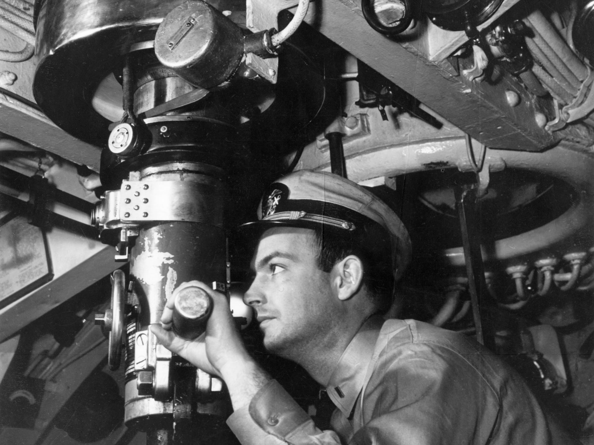 Navy officer looks through submarine periscope
