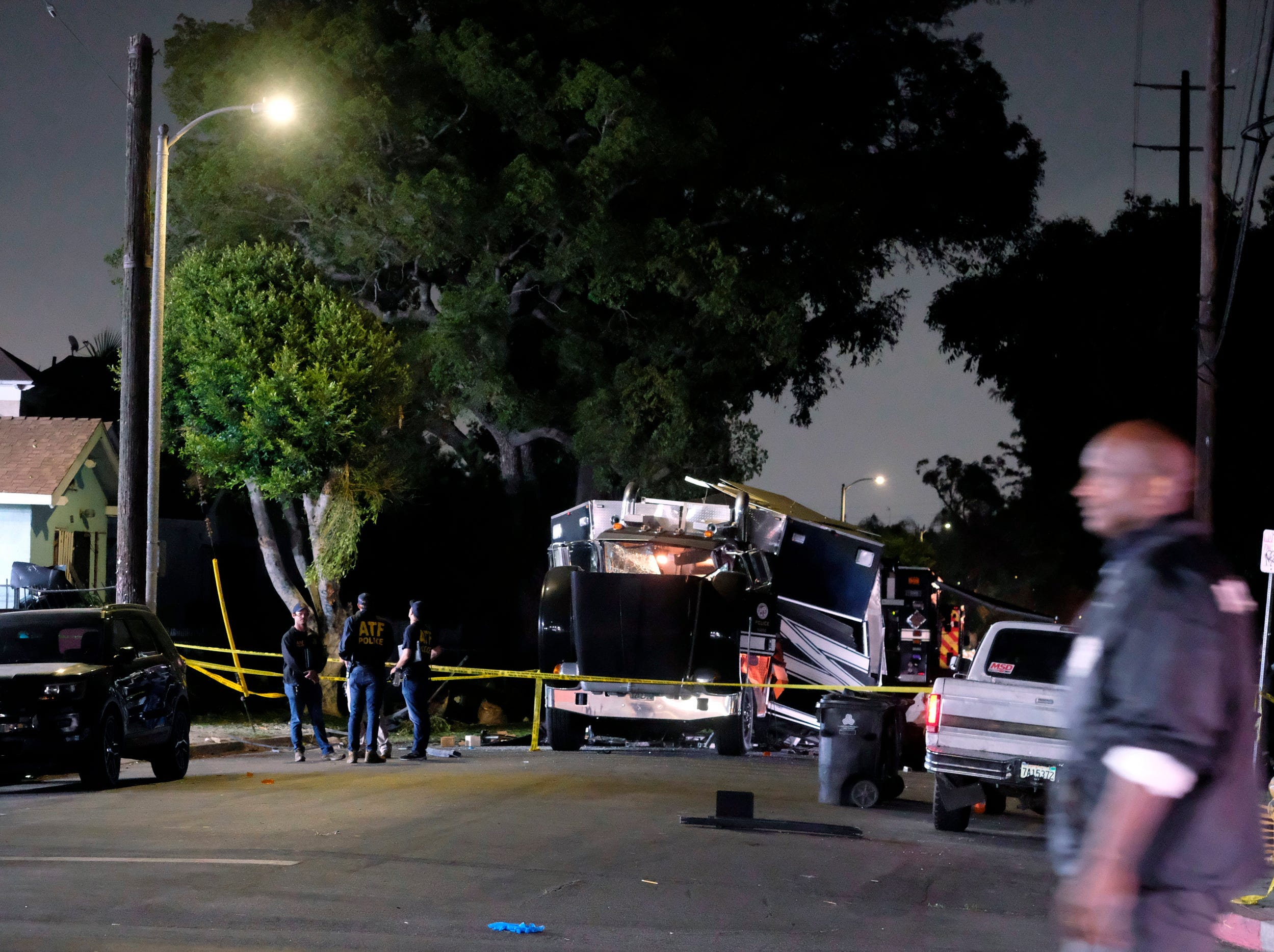 Photo of tractor-trailer damaged by explosion in the middle of the street and surrounded by police tape.