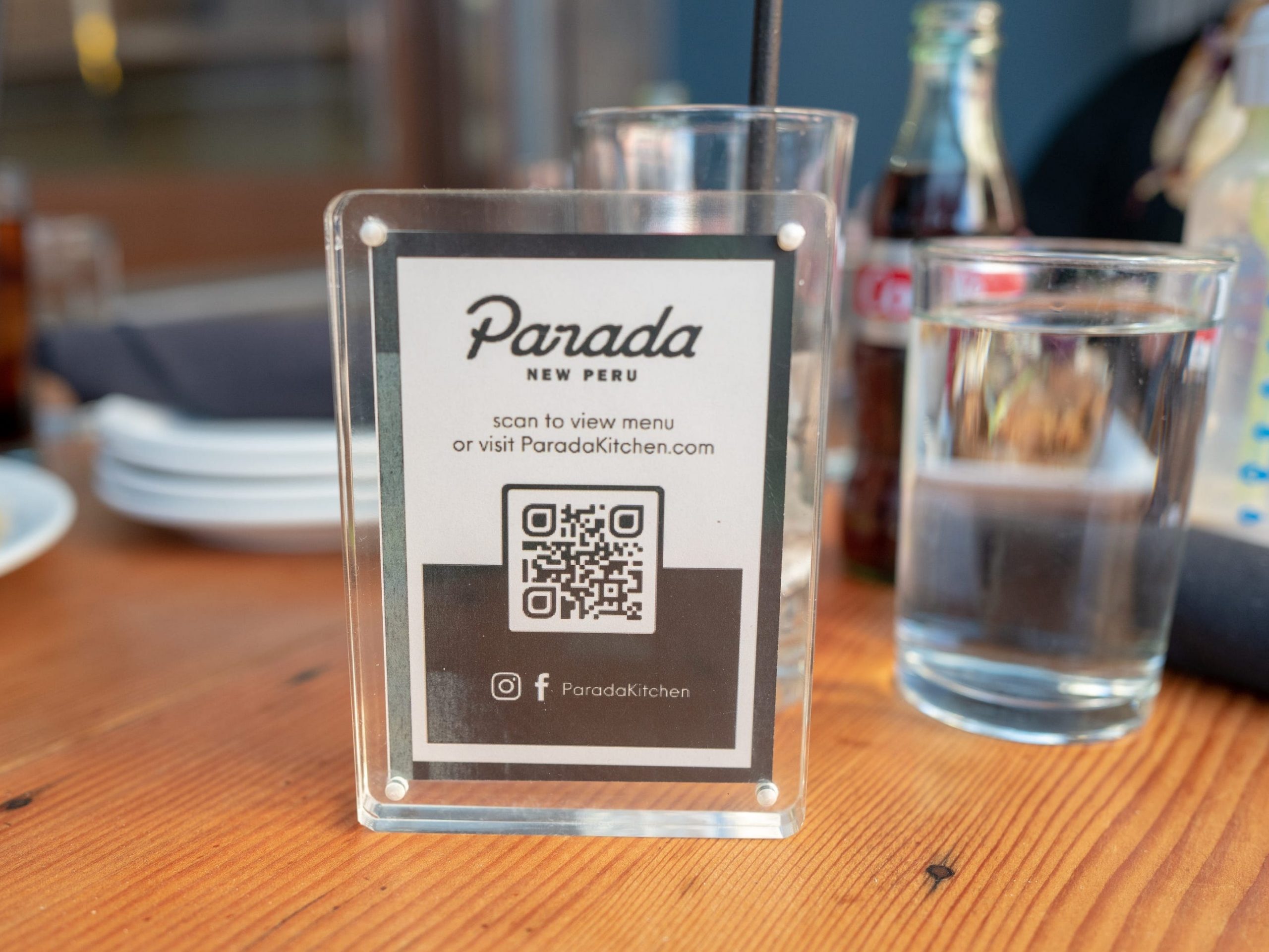 Close-up shot of a tabletop sign holder with a sign reading "Parada, New Peru" with a QR code visible at the Parada Kitchen Peruvian Restaurant in Walnut Creek, California, February, 2021