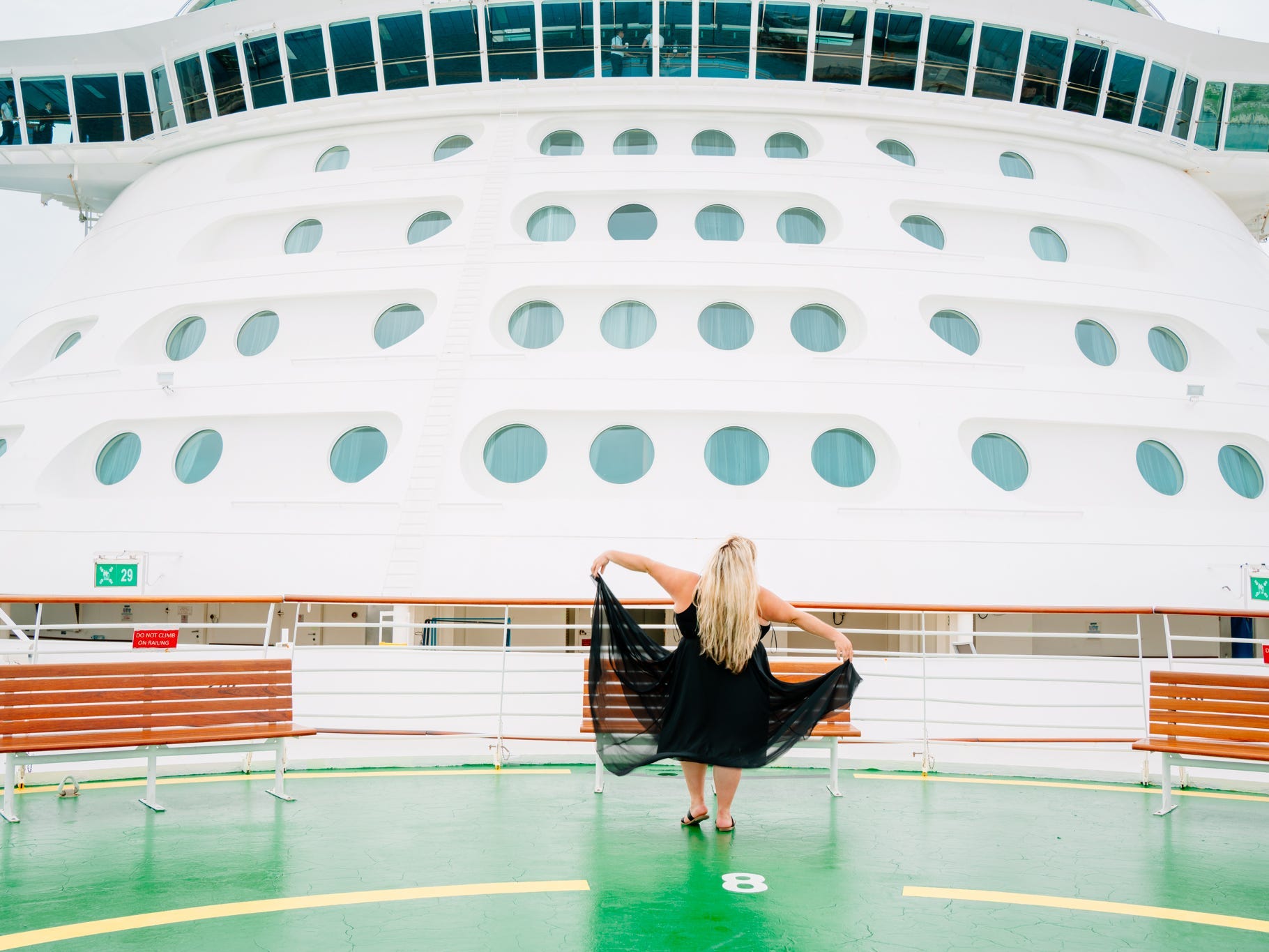 A woman standing on the deck of a cruise ship with her back to the camera
