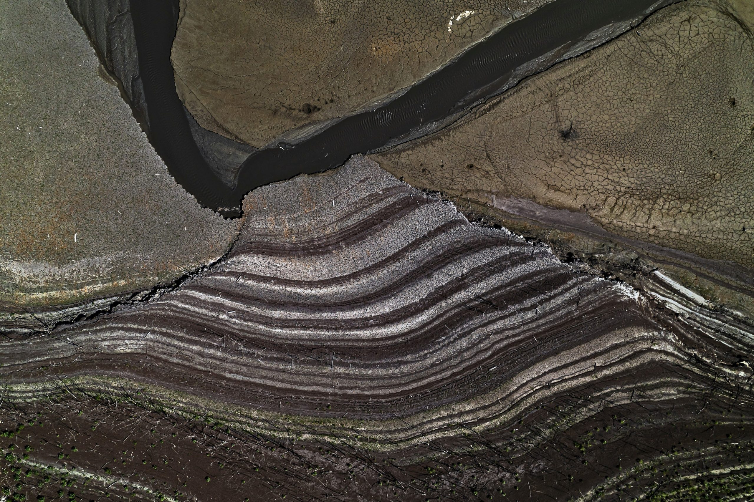 Rings are seen along rocks above a reservoir, showing where the water line once was.