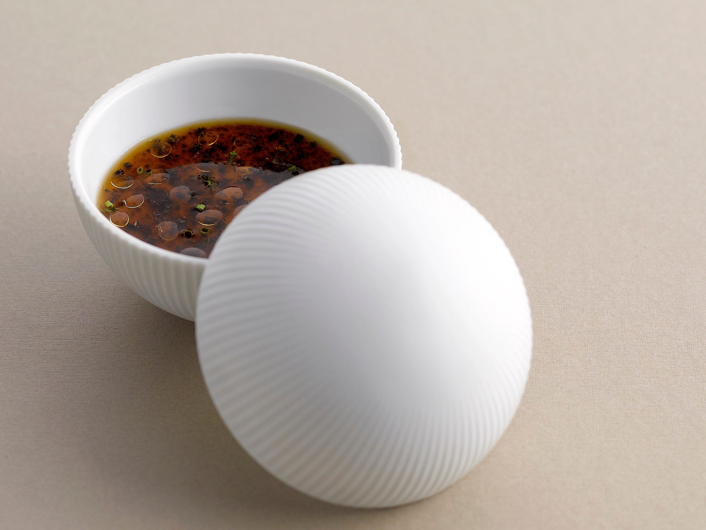 Chef Andre Chiang's classic "memory" dish is served in a white bowl with a white lid.
