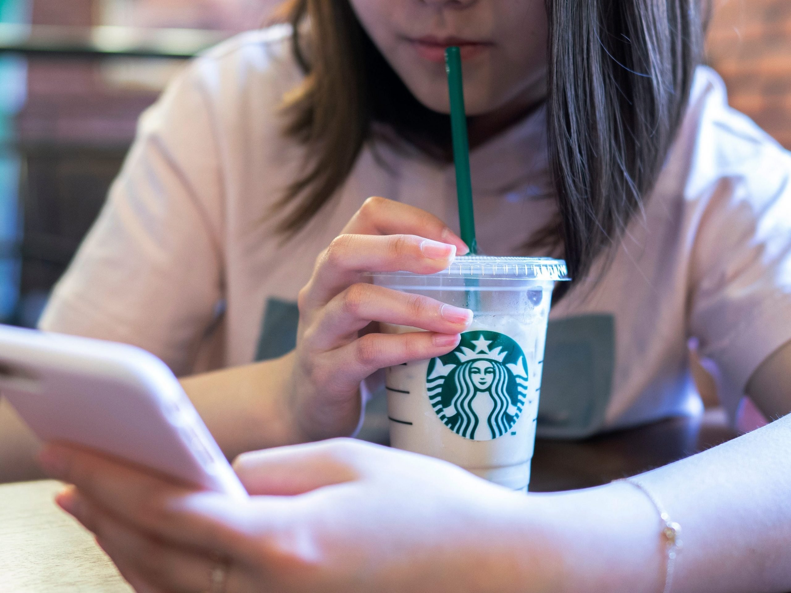 A girl is drinking ice coffee in a Starbucks coffee shop.