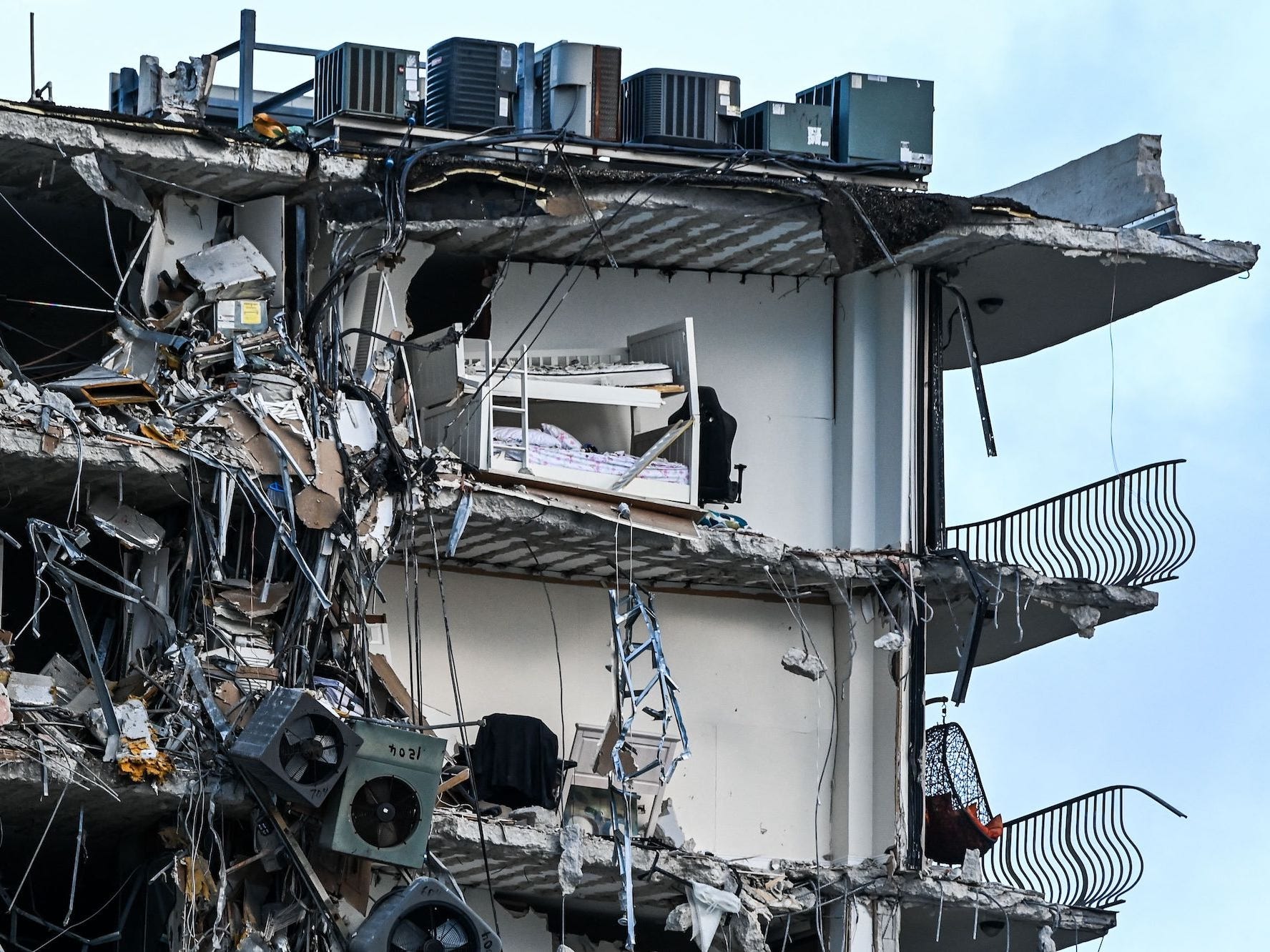 A bed can be seen in a split-open apartment as rubble hangs from a partially collapsed building in Surfside north of Miami Beach, on June 24, 2021.