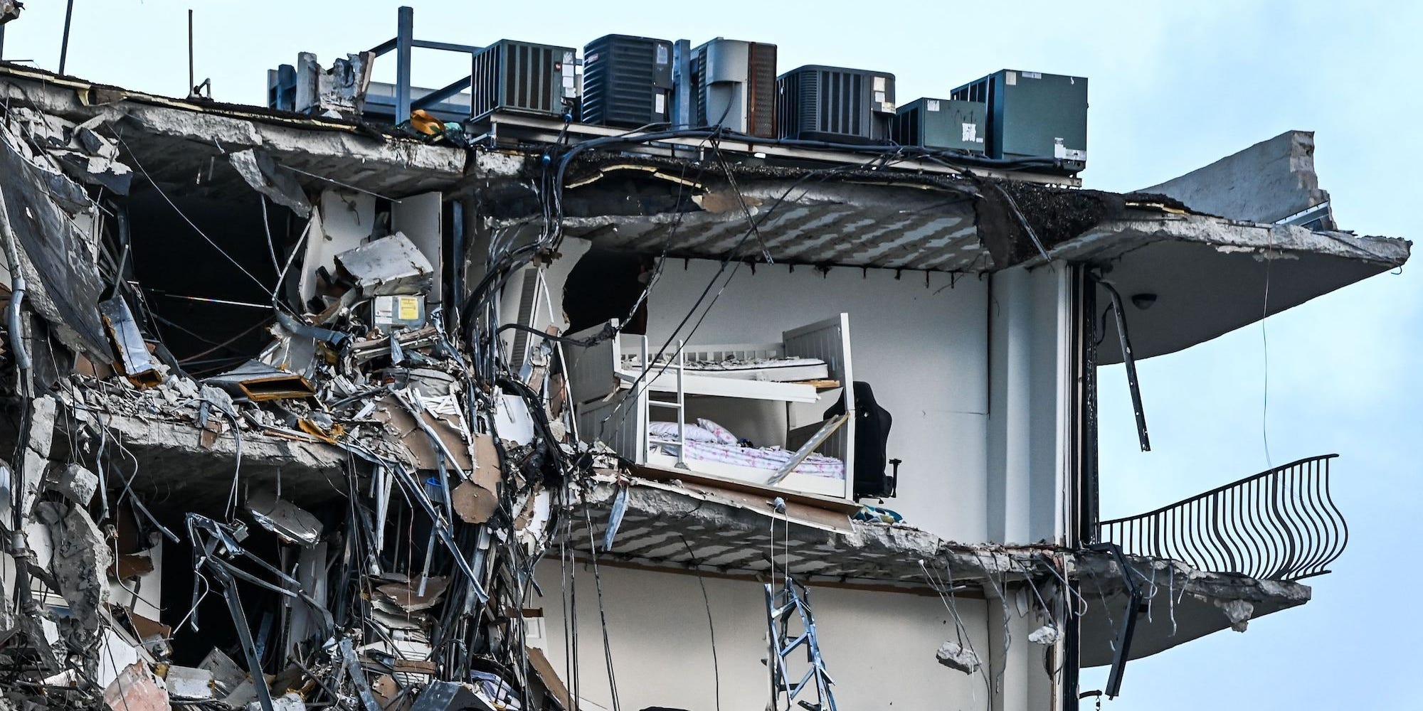 A bed can be seen in a split-open apartment as rubble hangs from a partially collapsed building in Surfside north of Miami Beach, on June 24, 2021.