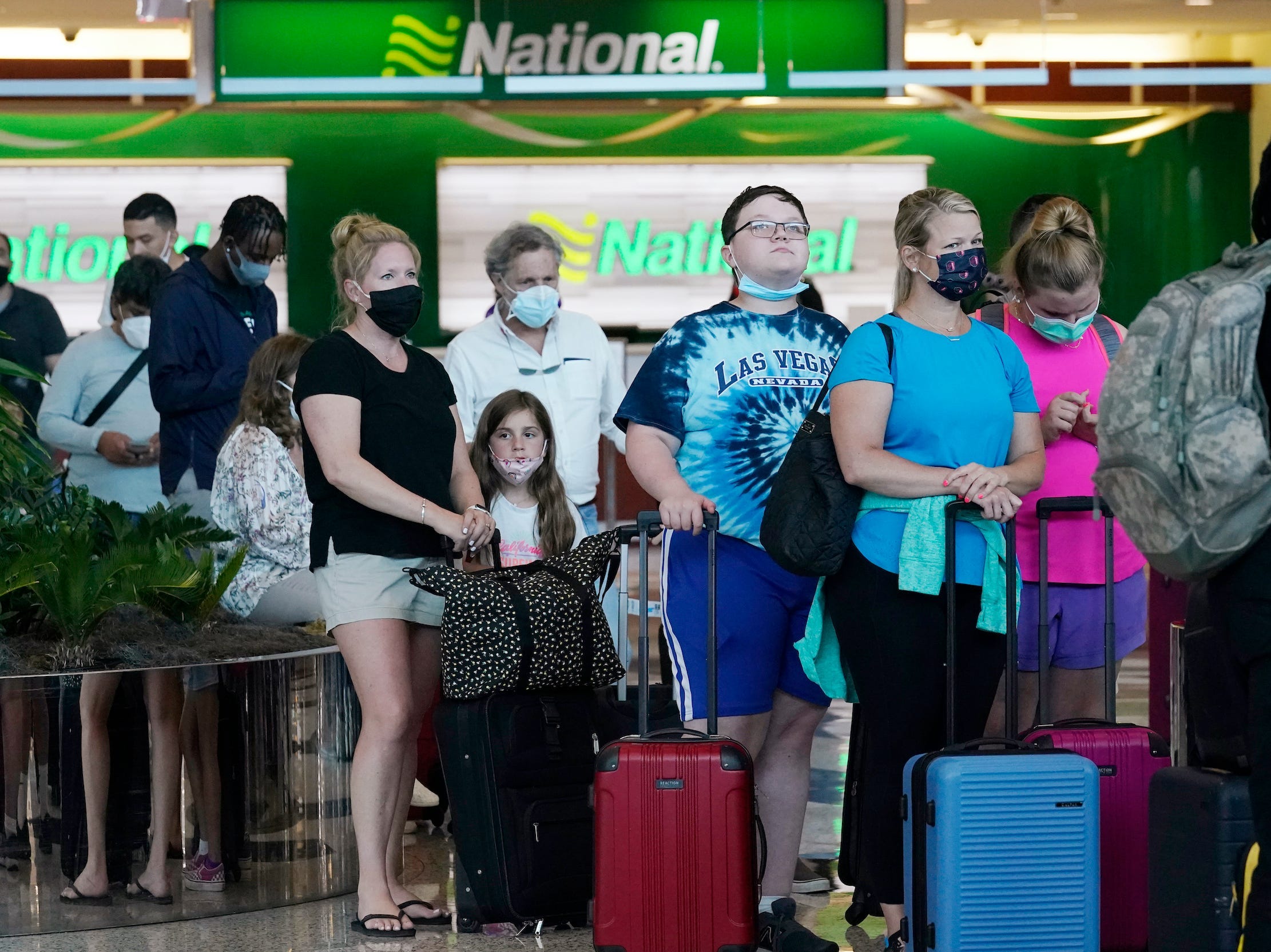 people waiting in line for rental cars in front of the National sign