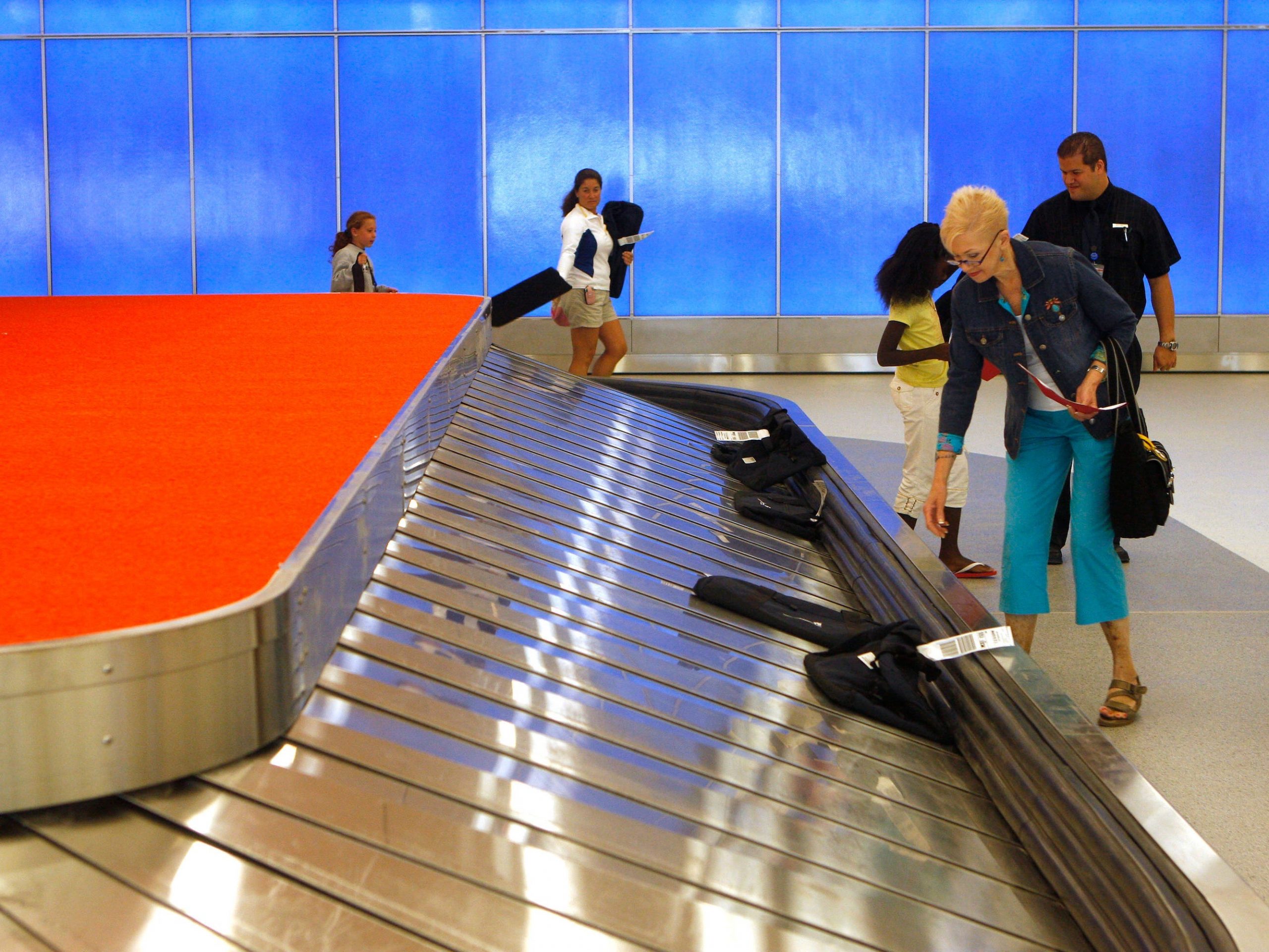 a woman stands at an airport carousel for checked baggage
