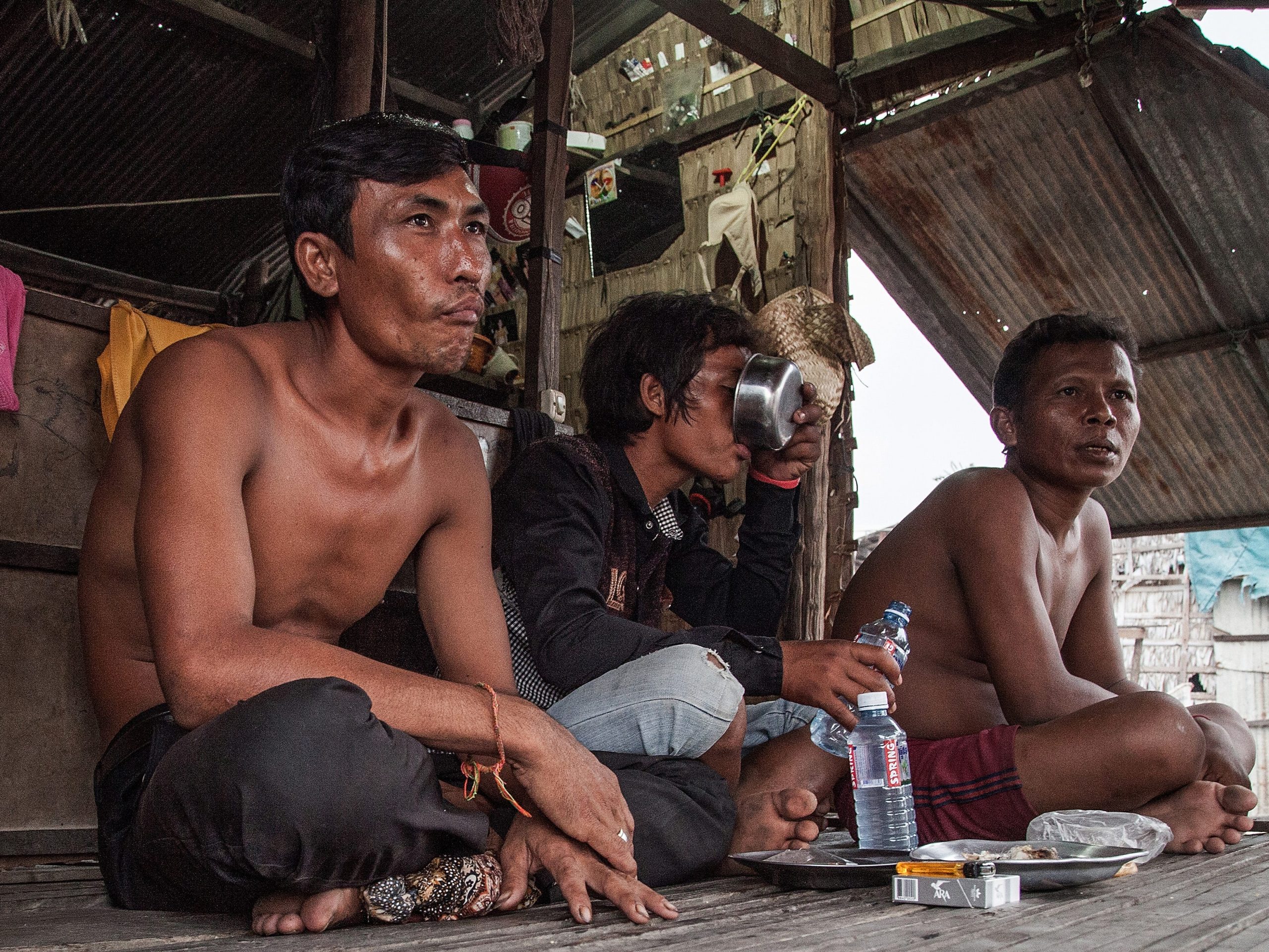 Three former fishermen drink rice wine in the floating village of Chong Kneas in Siem Reap, Cambodia, April 23, 2014 .