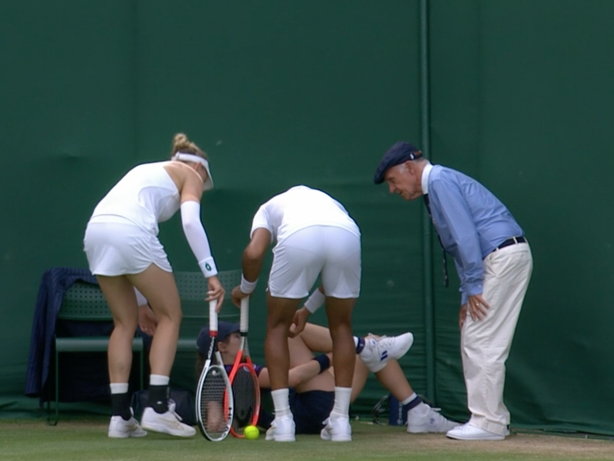 Players and an umpire see to a ball girl who slipped during Wimbledon