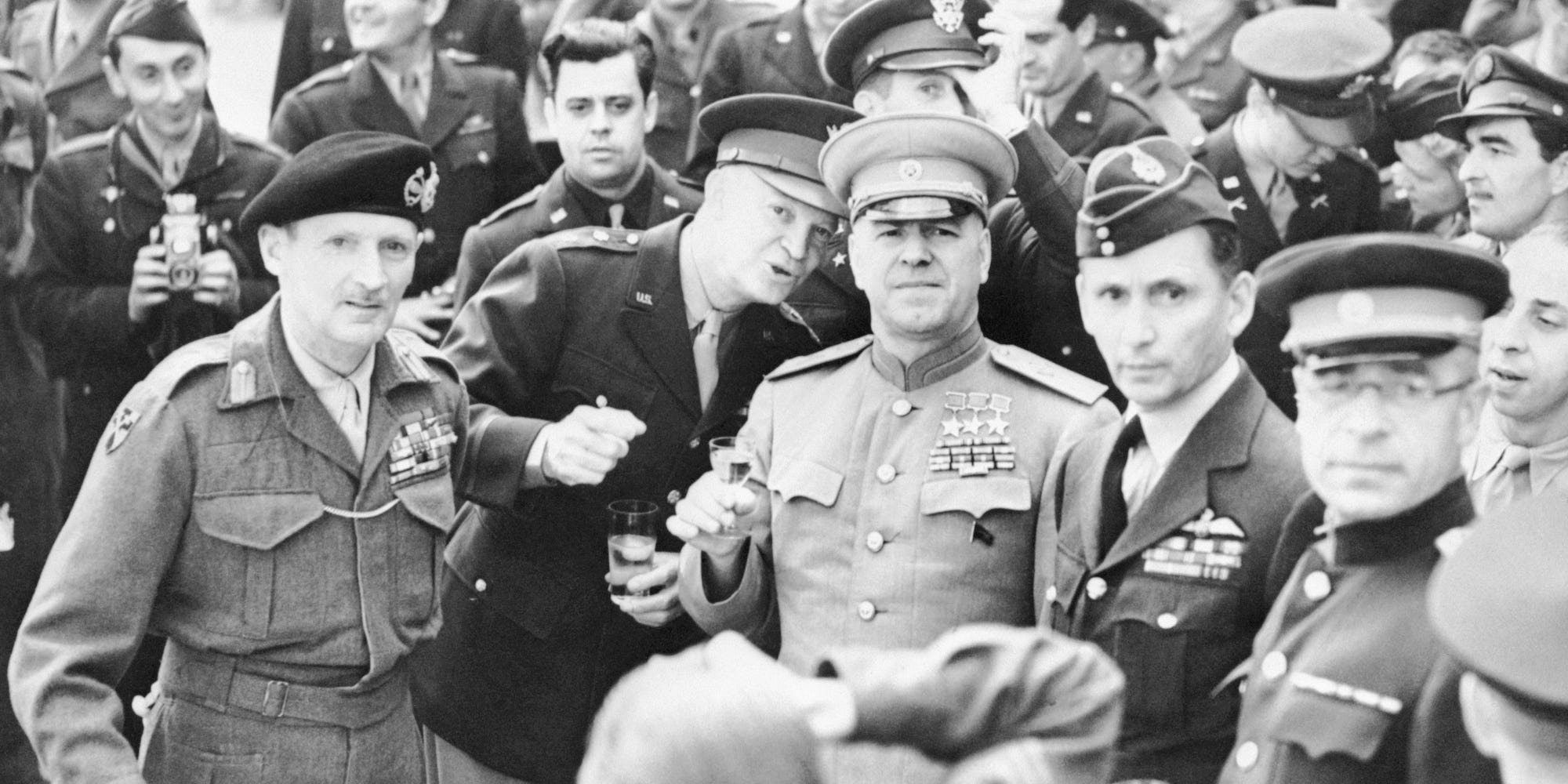 Dwight Eisenhower talks into Georgy Zhukov's ear while a third general, Bernard Montgomery, looks on. All three are holding glasses before a toast.