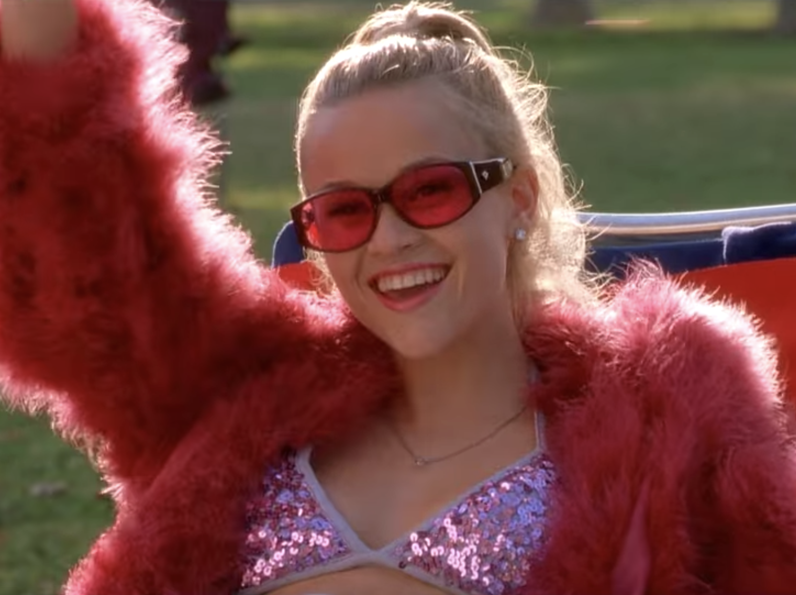 Reese Witherspoon wearing a pink outfit and holding a drink in "Legally Blonde."