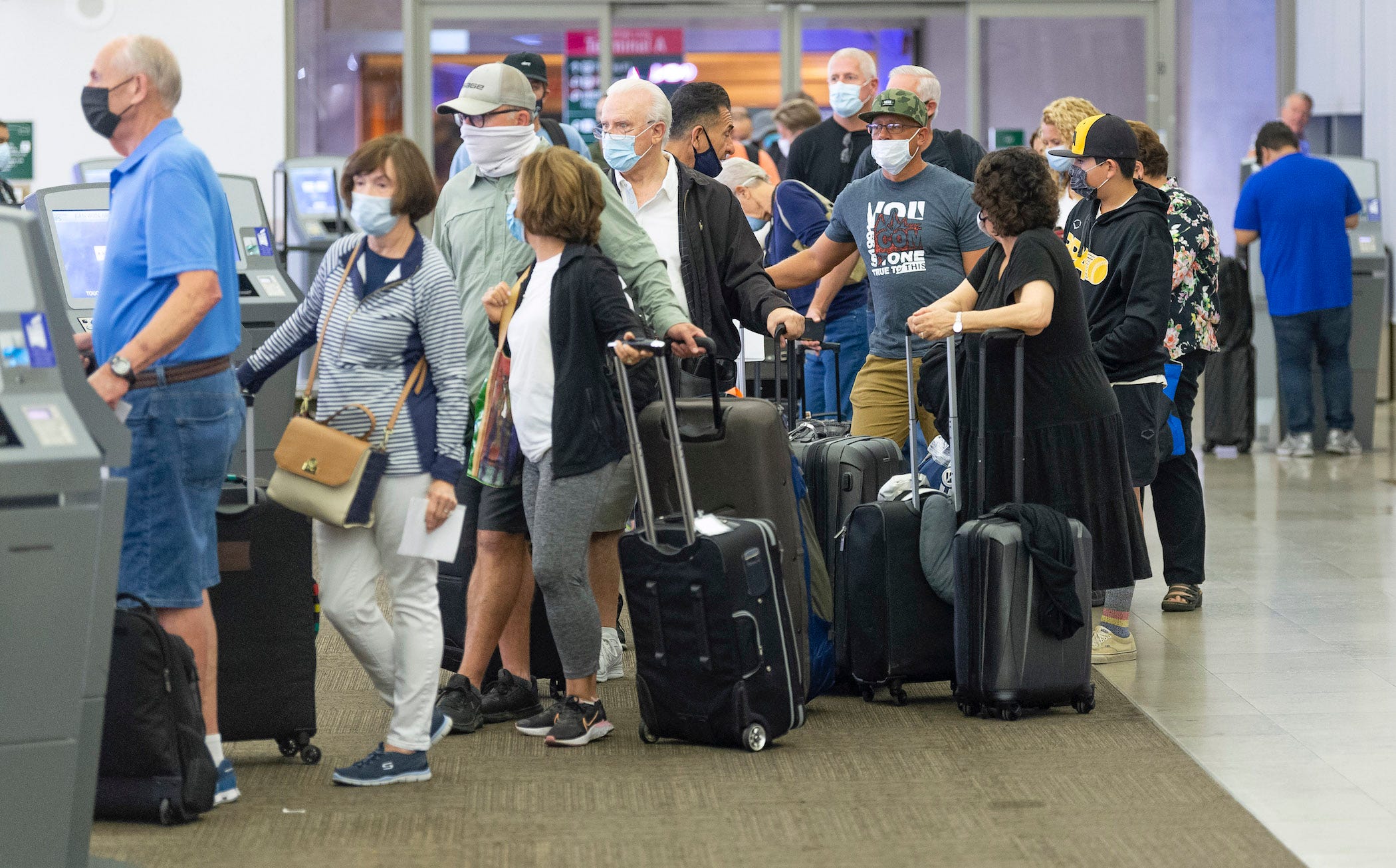 a crowded line of travelers with rollerbags waiting at john wayne airport in california