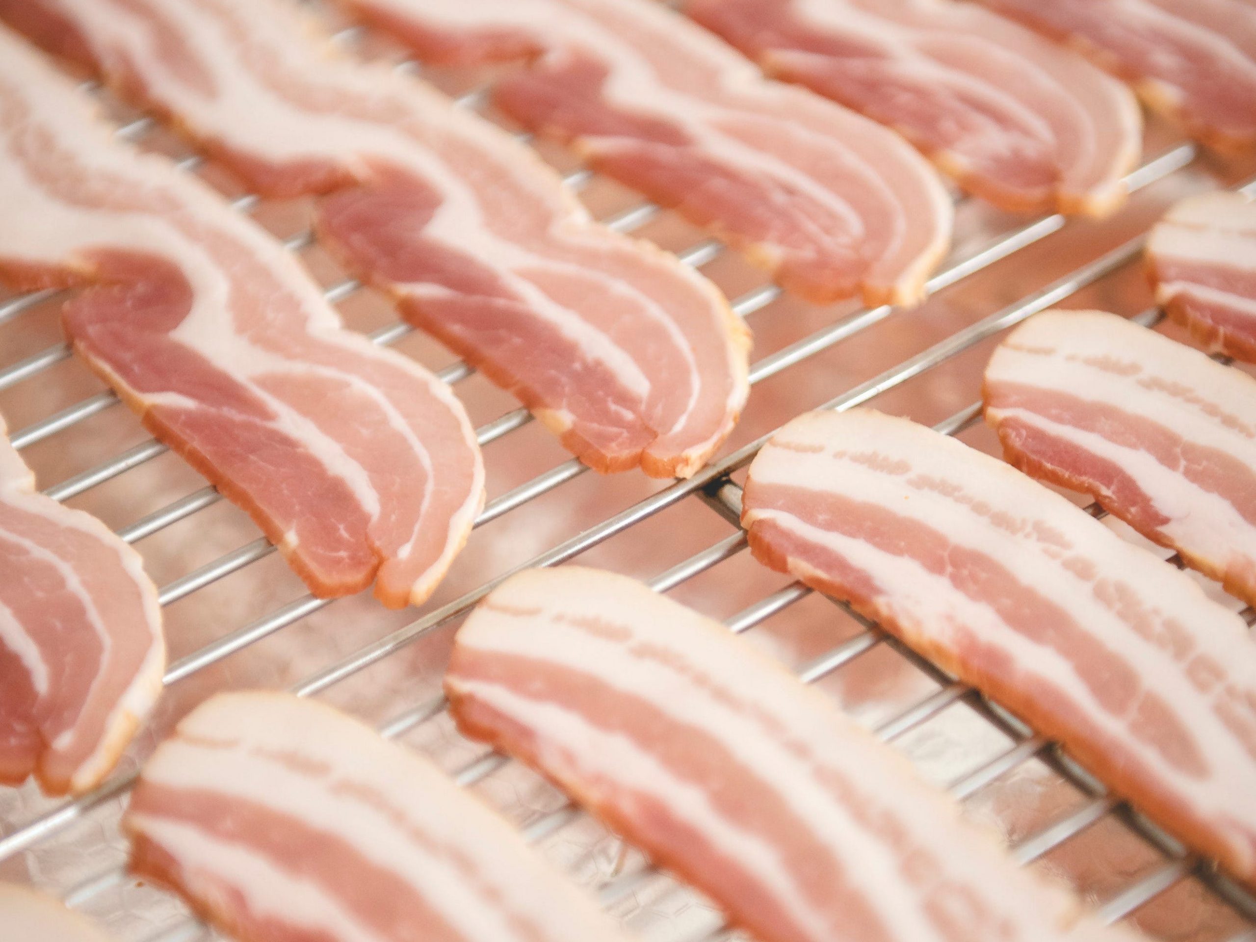 Strips of raw bacon laid out on a wire rack