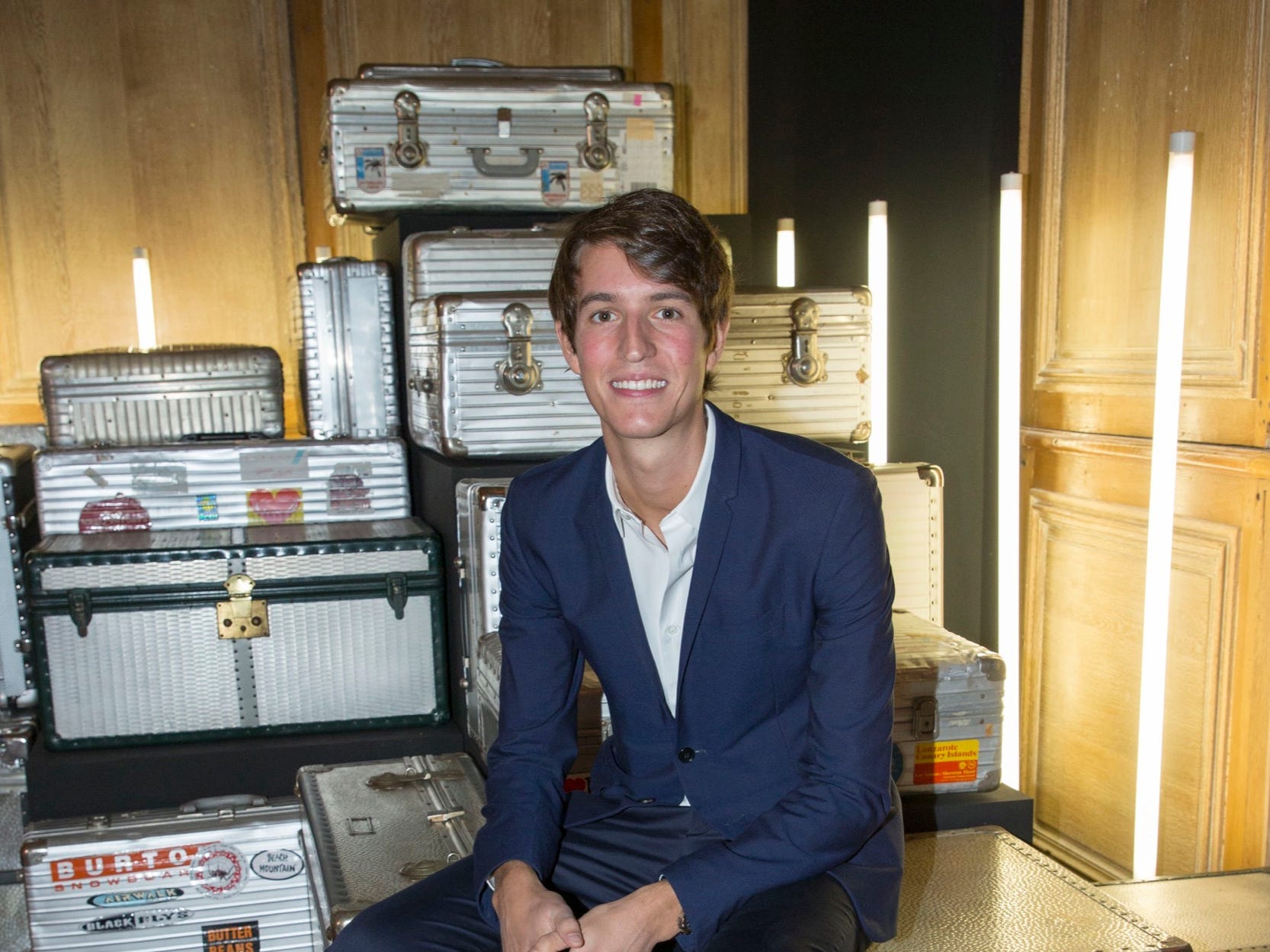 alexandre arnault sits in front of a stack of aluminum rimowa suitcases