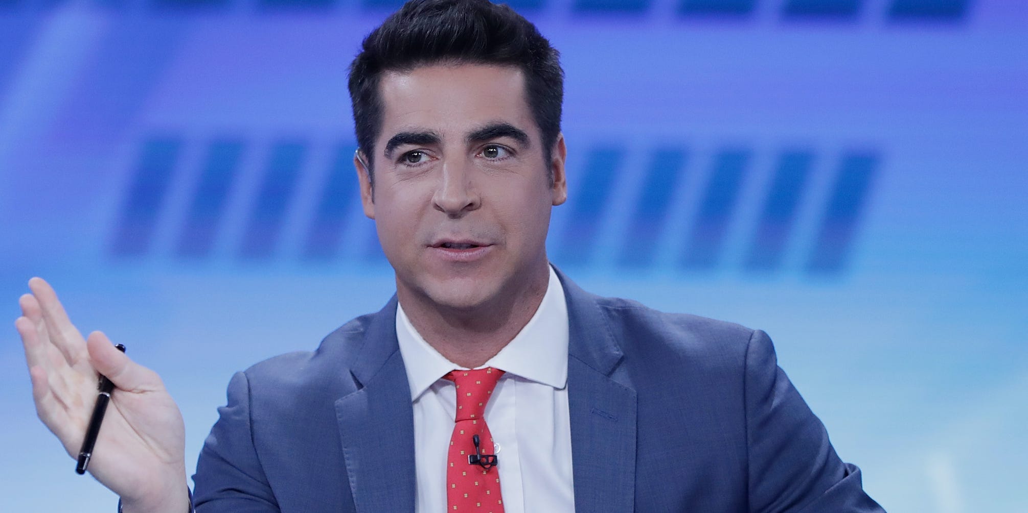 Fox News host Jesse Watters gestures with a pen in his right hand.