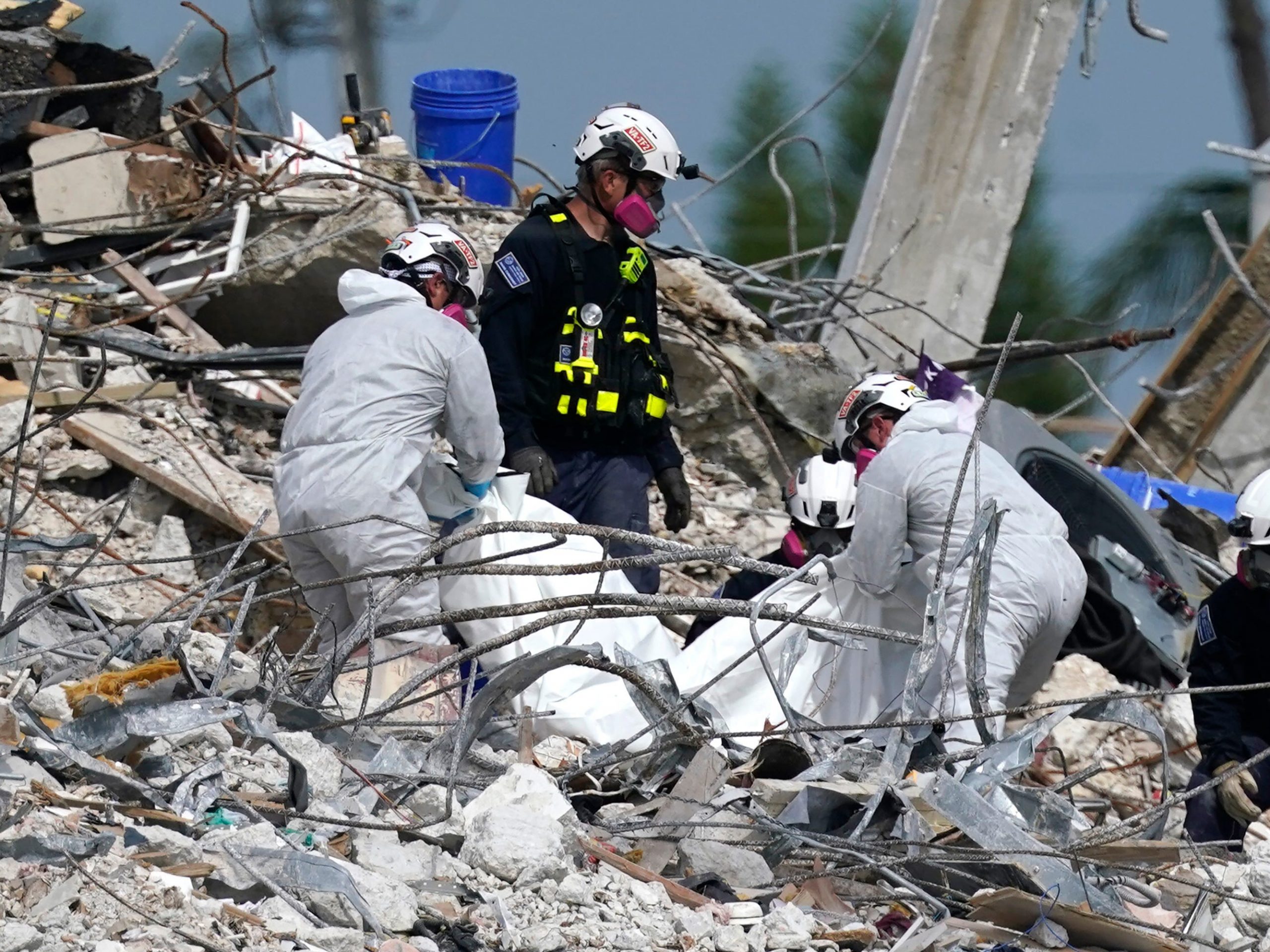 Rescue workers use a tarp for recovered remains at the site of the collapsed Champlain Towers South condo building.