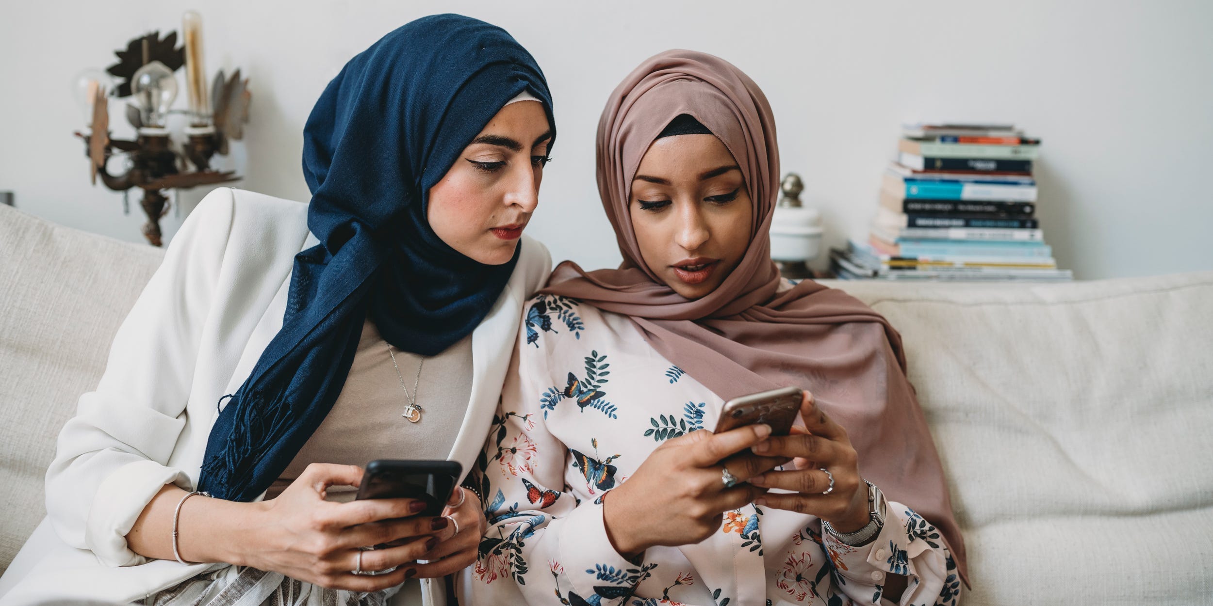 Two people looking at phones on a couch