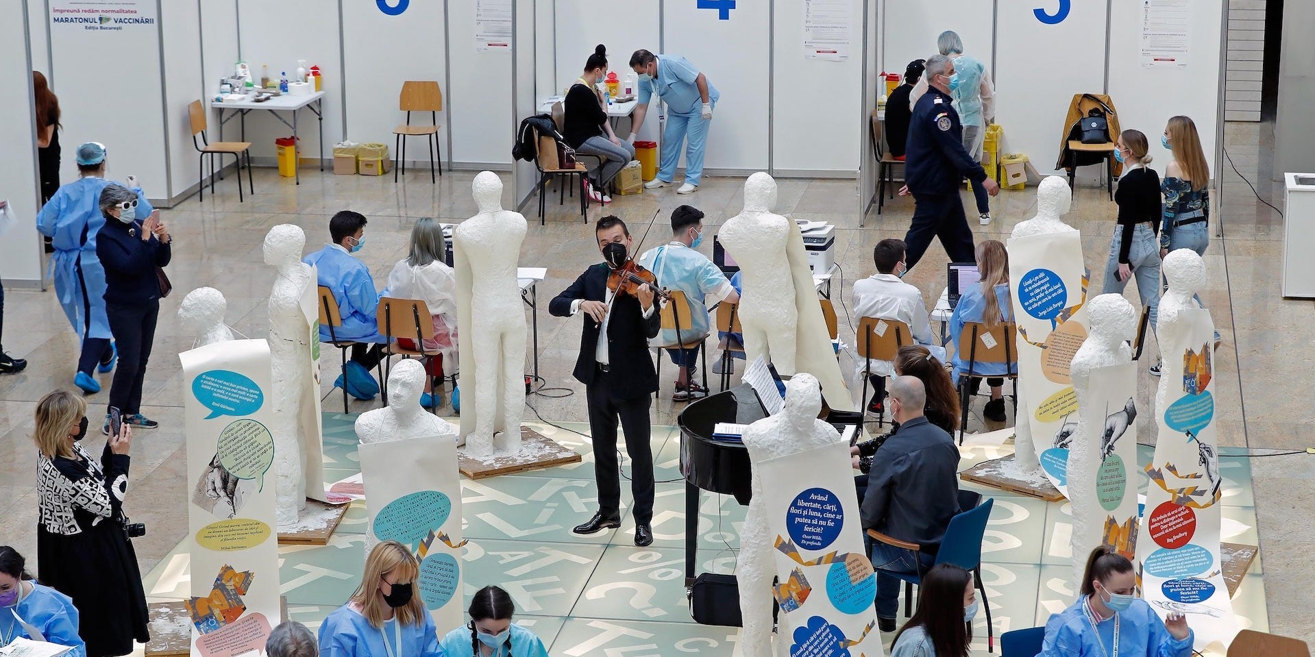 Romanian violinist Alexandru Tomescu in a tuxedo is playing as people around him are getting vaccinated in vaccination center in Bucharest, Romania on May 7, 2021.