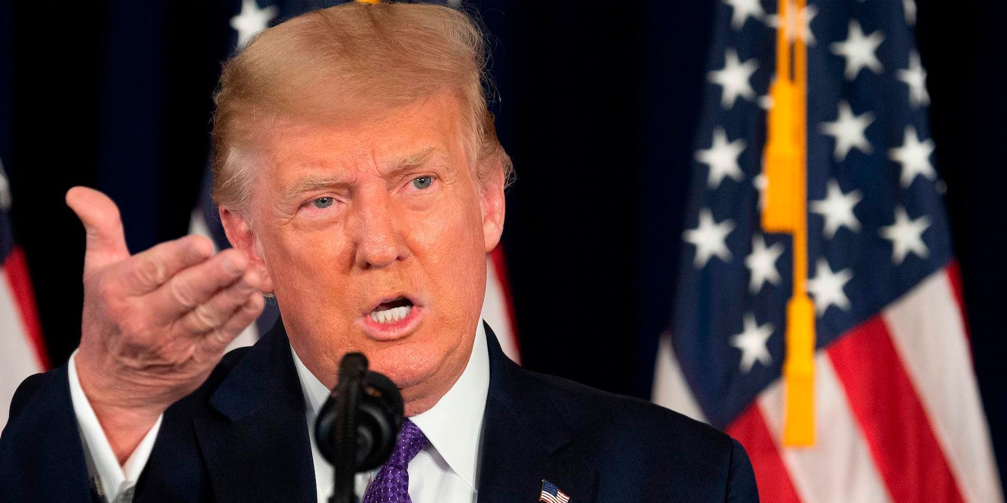 Former President Donald Trump gestures up with his right hand and sidewalk with his left.