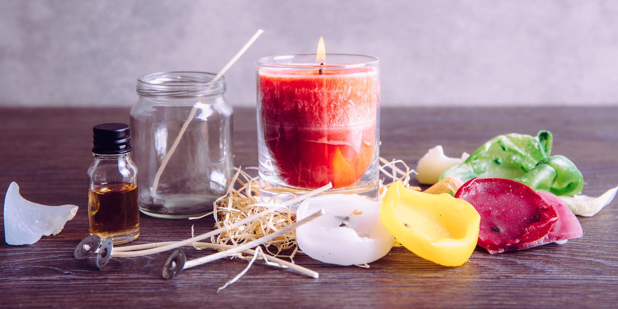 Candle-making materials laid out on a table with a lit candle at the center