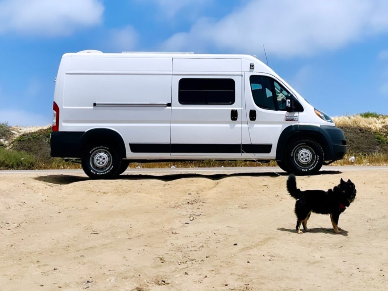 white van in front of a bright blue sky on sand