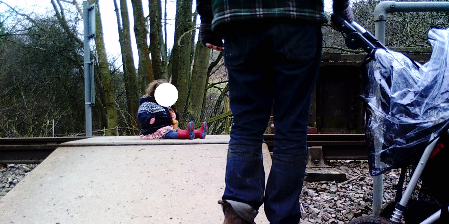 Parents taking photo of child of railway crossing.