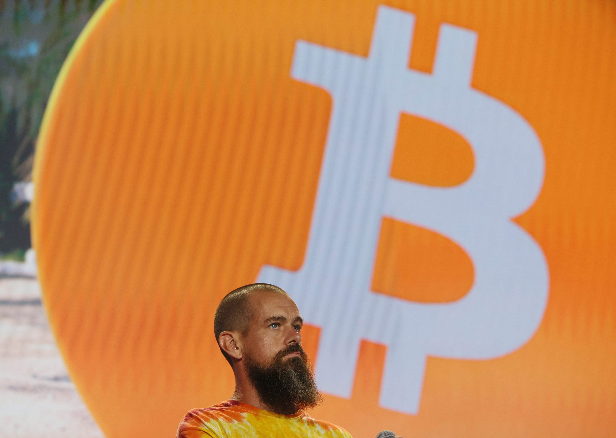 Square and Twitter CEO Jack Dorsey wearing a tye-dye shirt on stage in front of a bitcoin logo at a bitcoin convention in Miami, Floridia, on June 4, 2021.