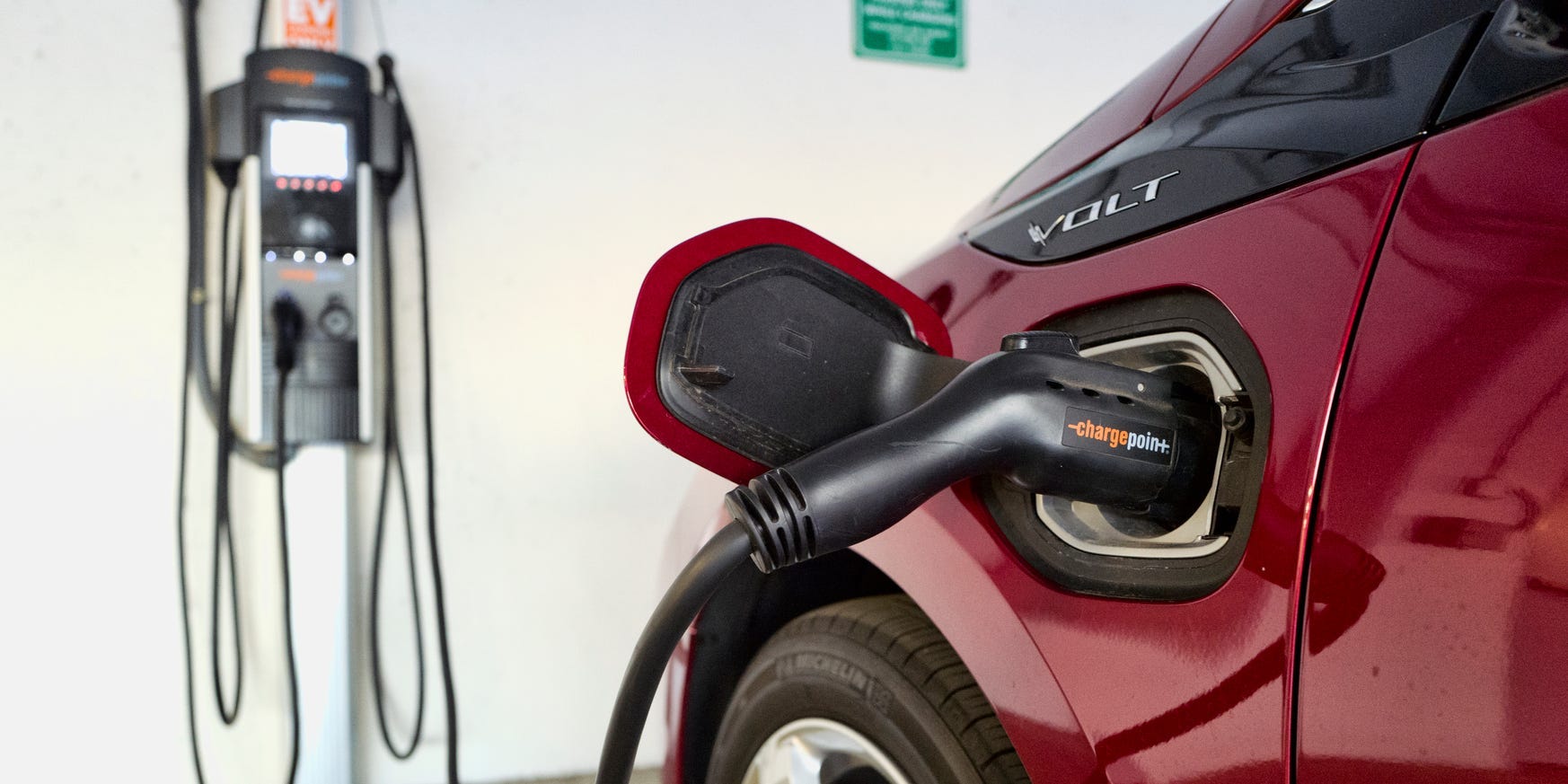 A red Chevrolet Volt hybrid car is charging in a parking garage.