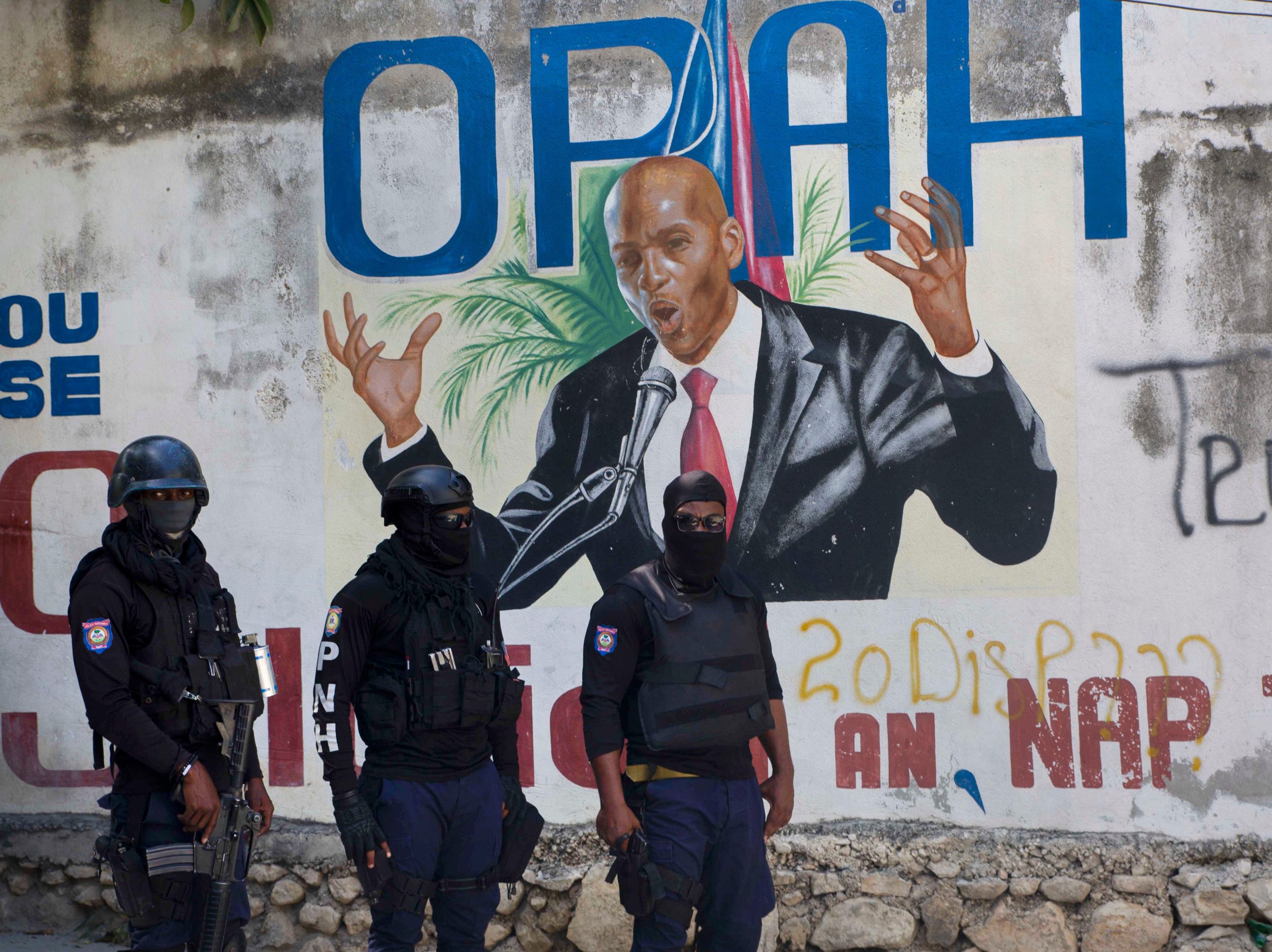 Armed police officers stand in front of a mural of Haitian President Jovenel Moïse