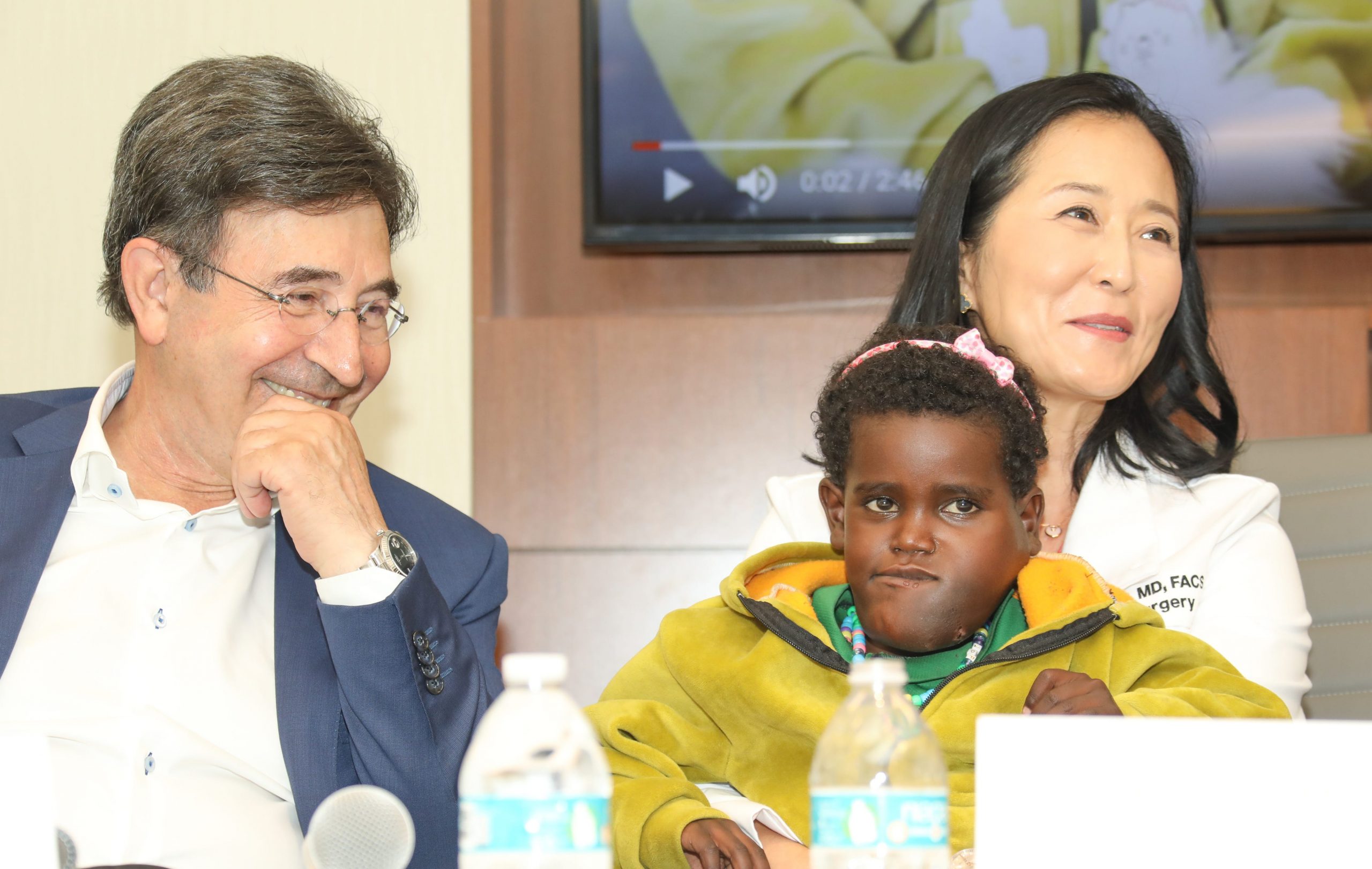 Surgeons sit with their patient during a press conference.