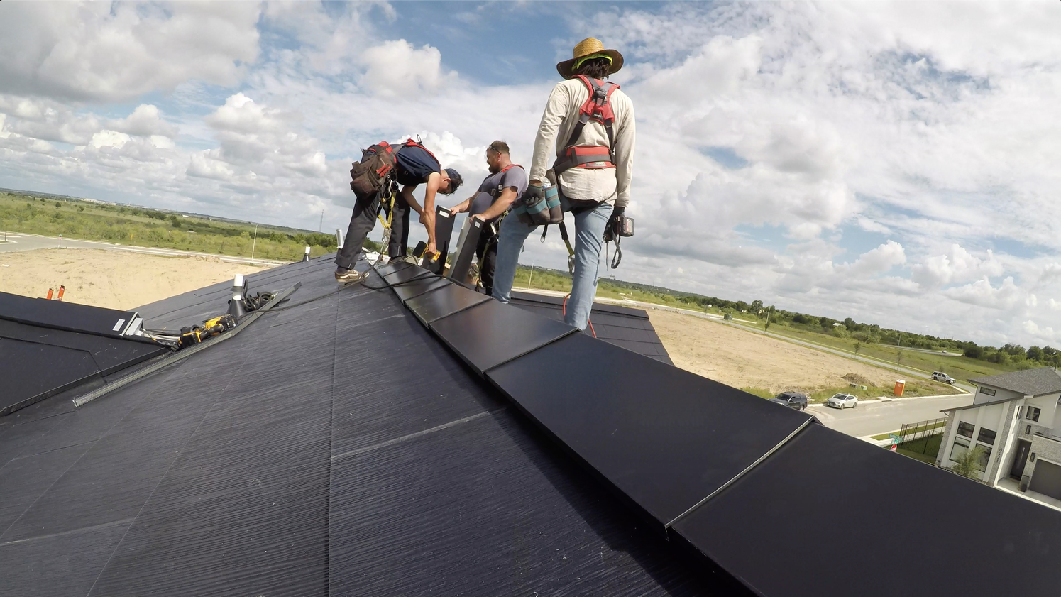 Workers installing a Tesla Solar Roof on a home in the SunHouse at Easton Park community.