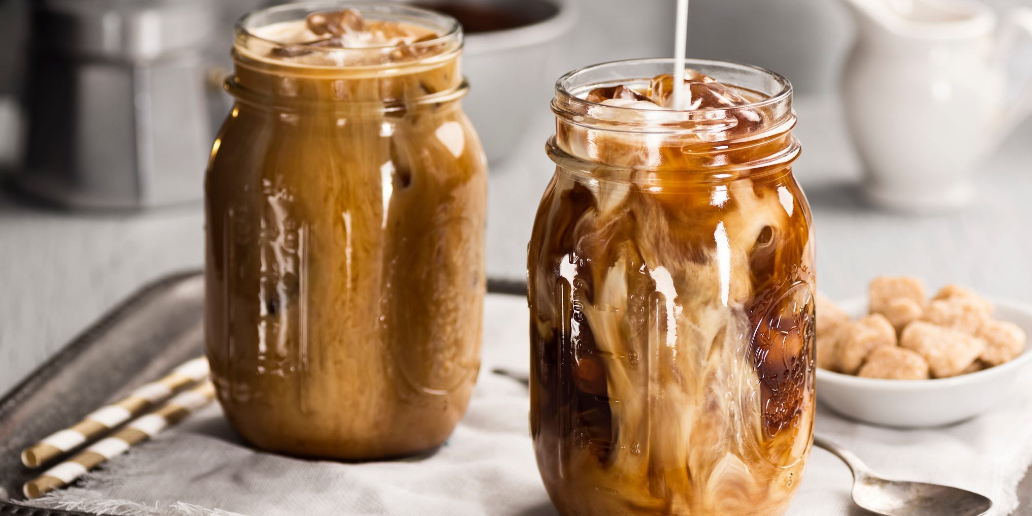 Cream being poured into a mason jar of iced coffee