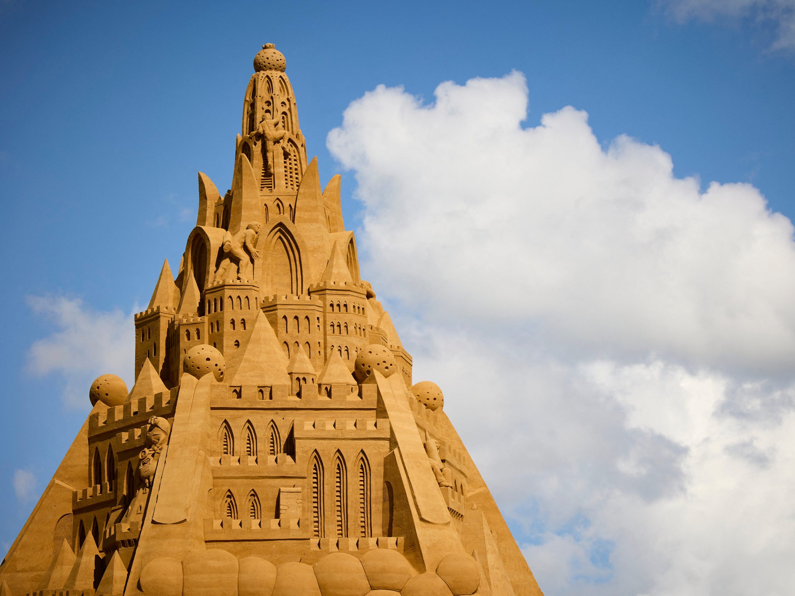 The top section of a massive sandcastle with intricate designs in the sand sculpture.