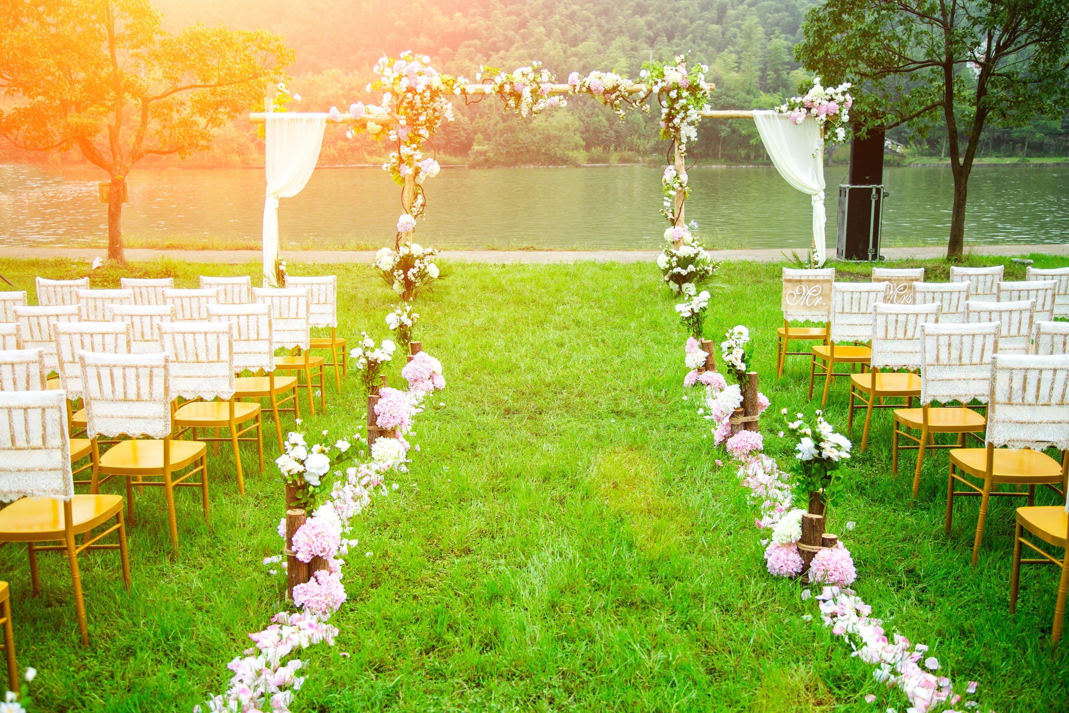 outdoor wedding space set up for guests with white chairs, flowers, and altar